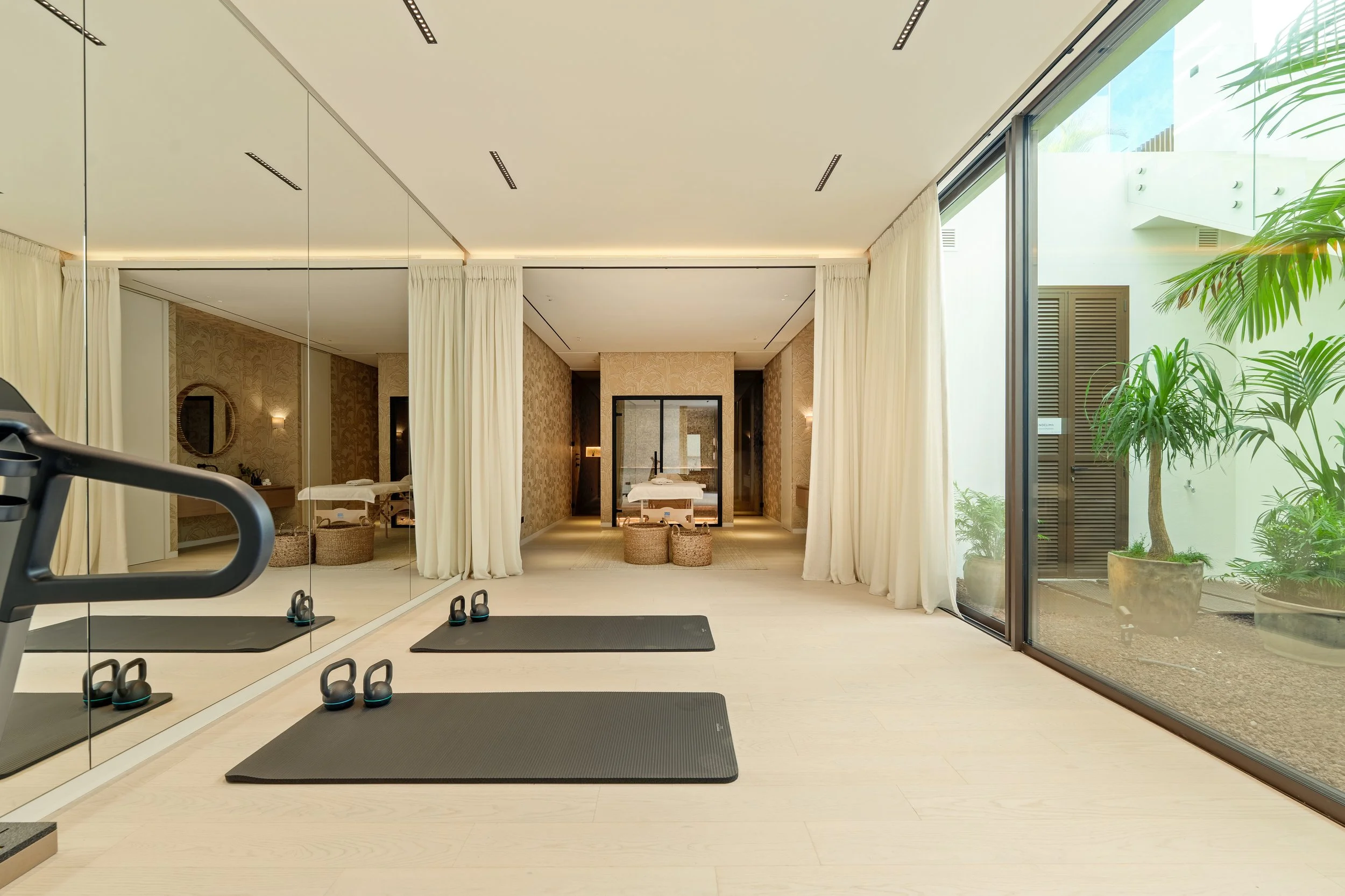 Home gym and yoga studio with full-length mirrors and sliding glass doors leading to a courtyard.