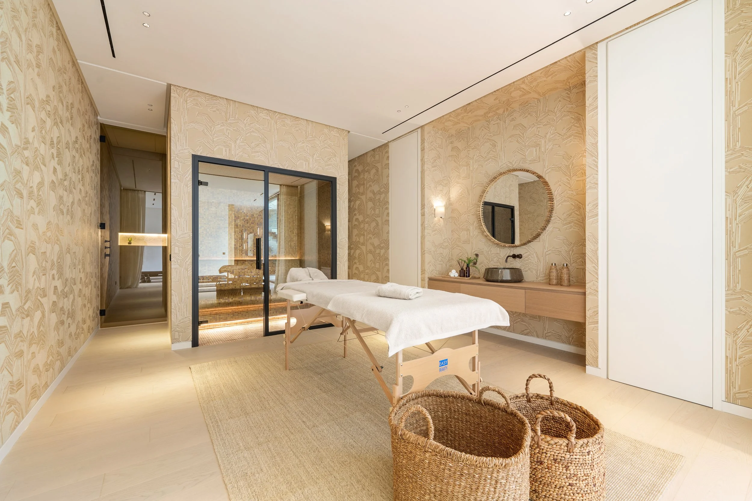 Dedicated spa and treatment room featuring a massage table and organic textured stone walls.