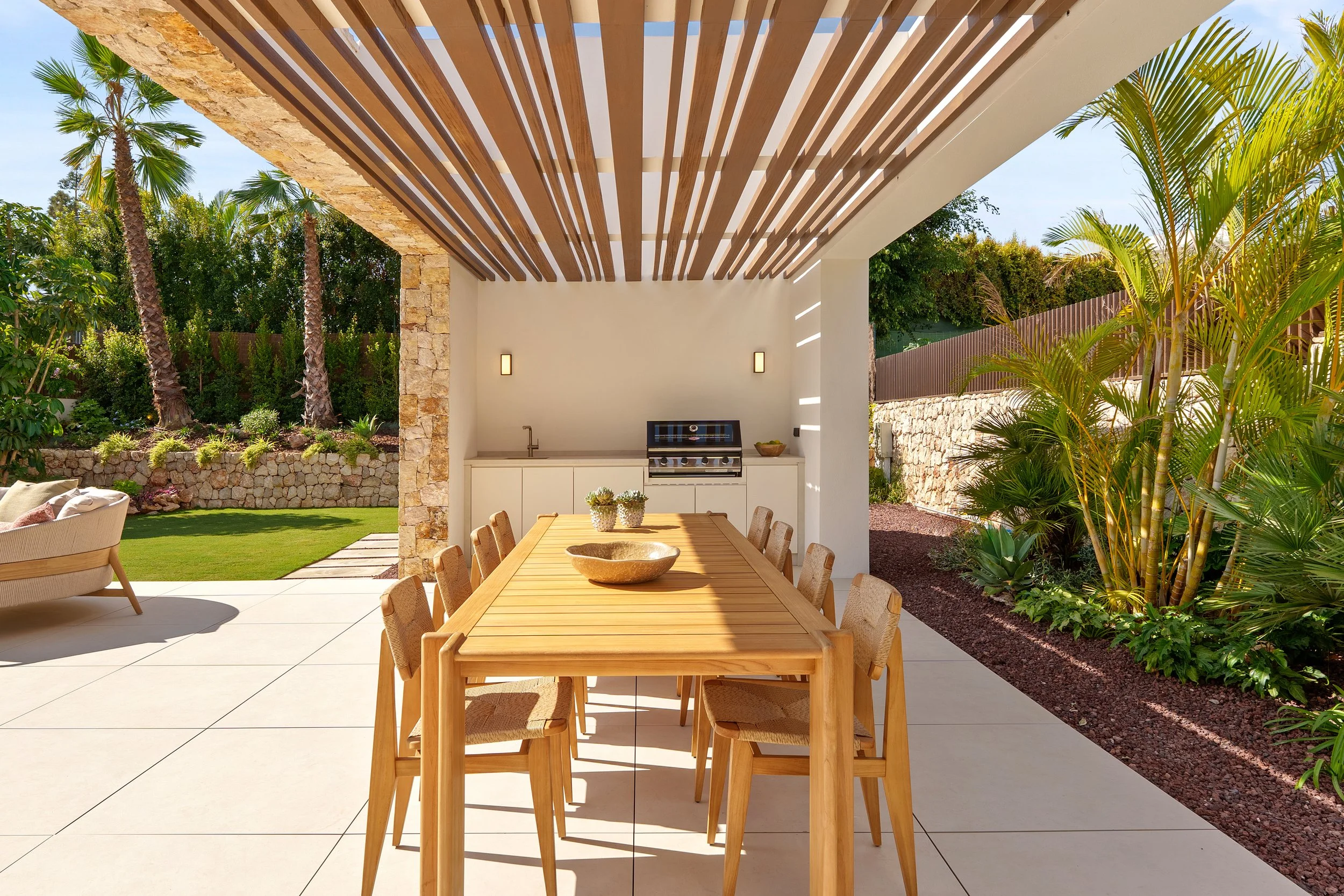 Outdoor dining area with a wooden slat pergola and a contemporary table set for alfresco entertaining.