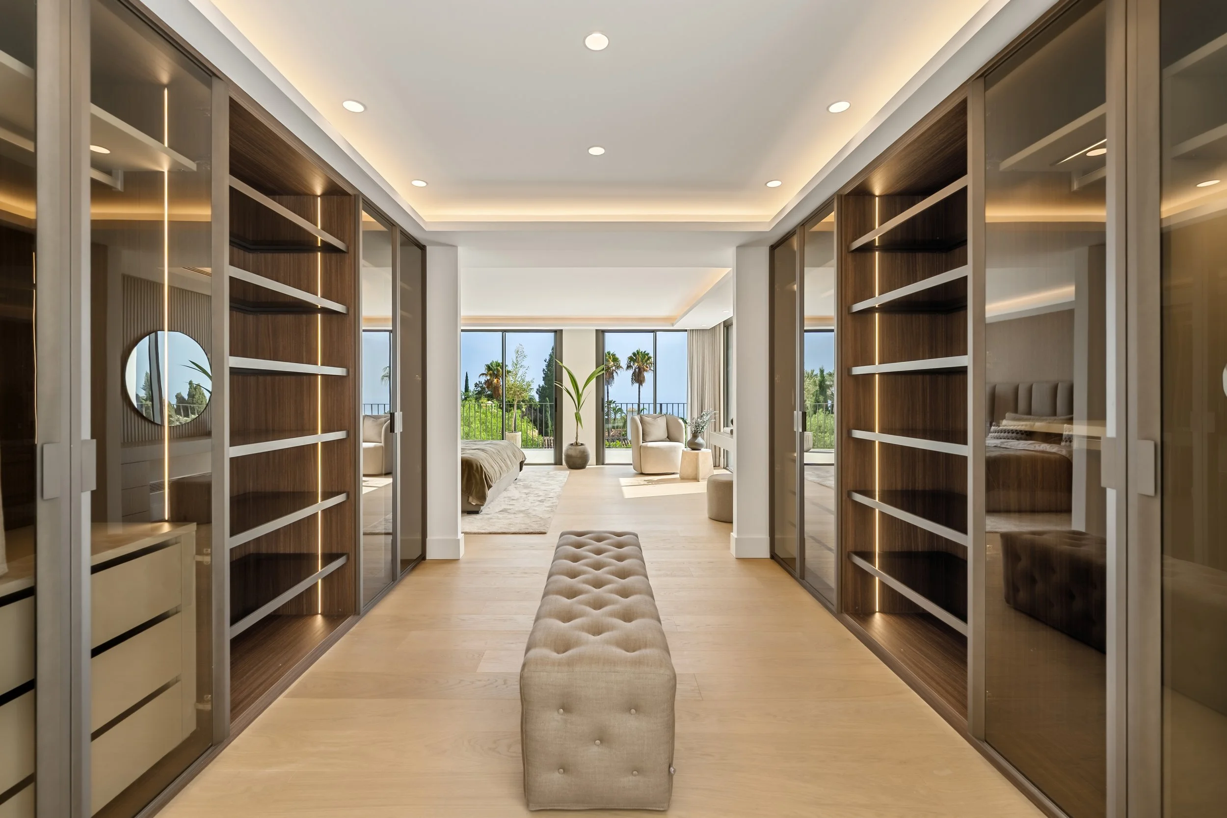 Professional walk-through dressing room with custom wood cabinetry and integrated boutique-style lighting.