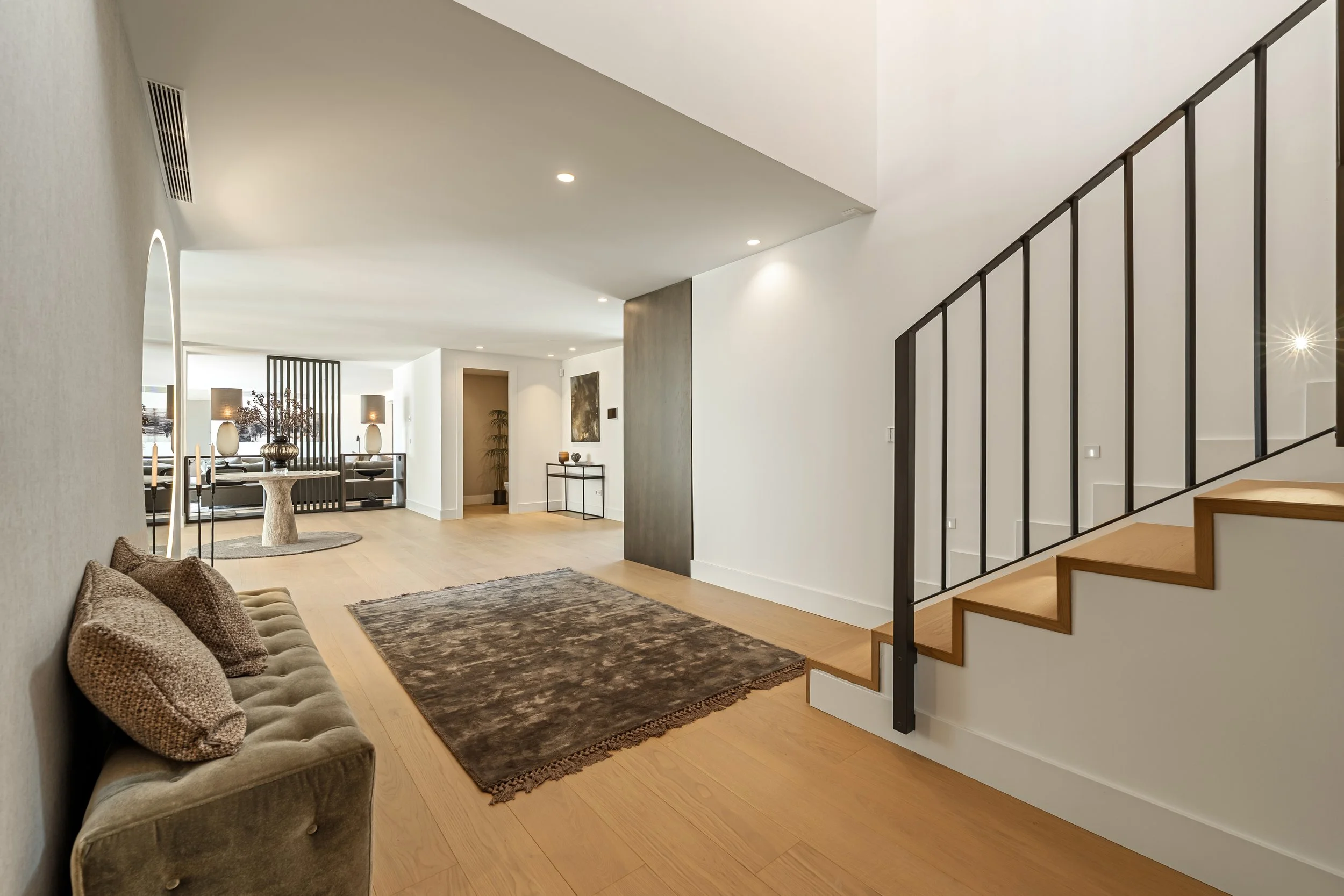 Minimalist entrance hall featuring a floating wooden staircase with sleek black metal railings.