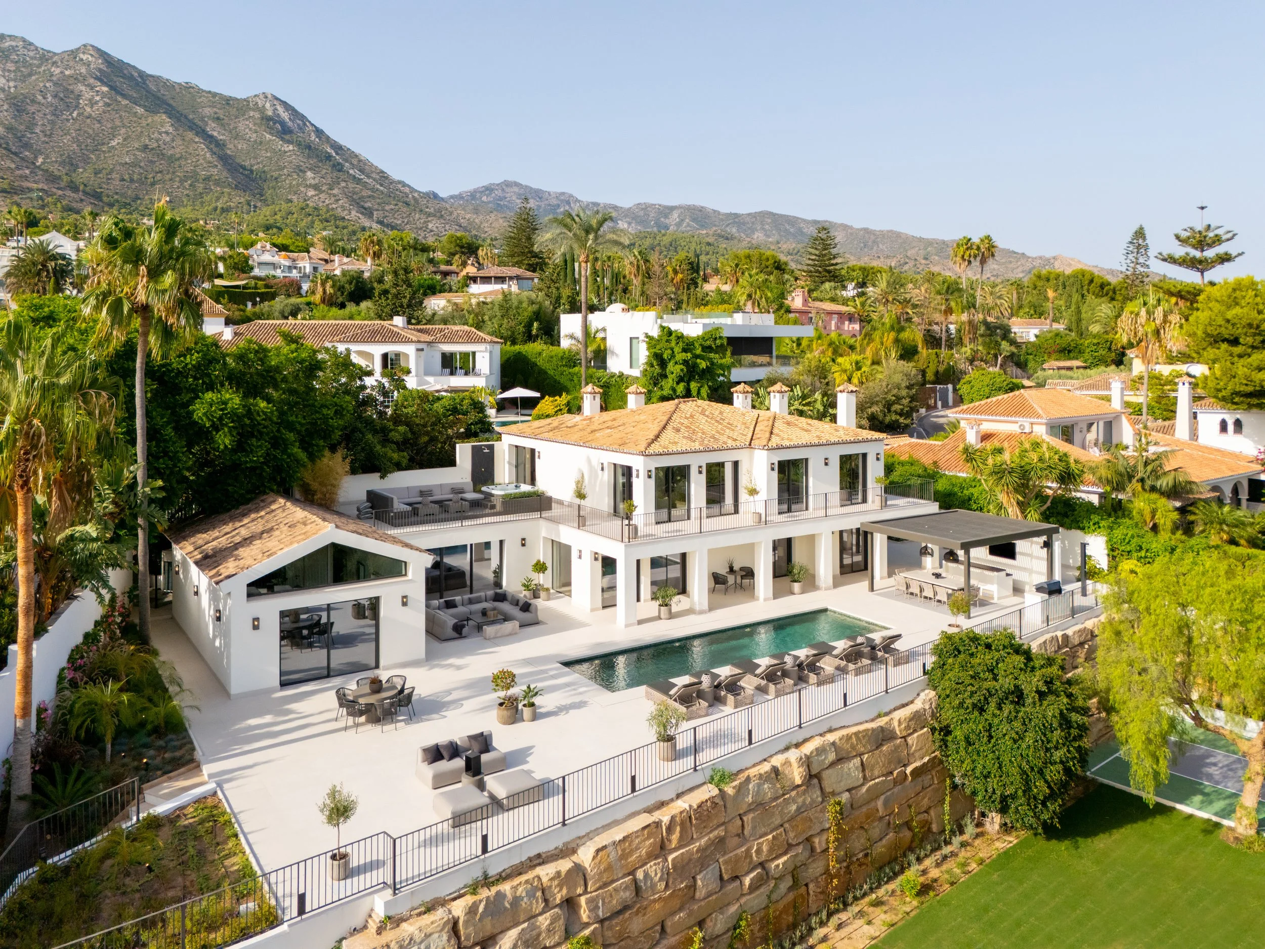 levated aerial view of a white contemporary Andalusian villa with a swimming pool, nestled in the lush greenery of Rocío de Nagüeles.
