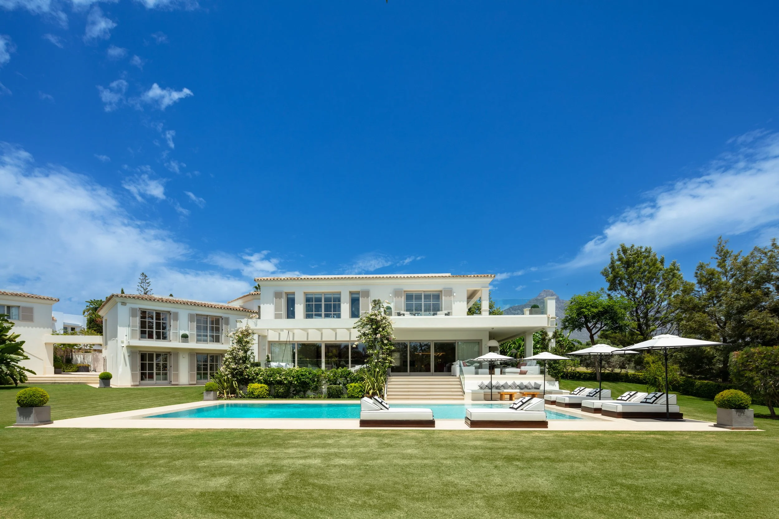 Elevated view of the white timeless mansion and private pool set against the dramatic backdrop of Marbella’s La Concha mountain.