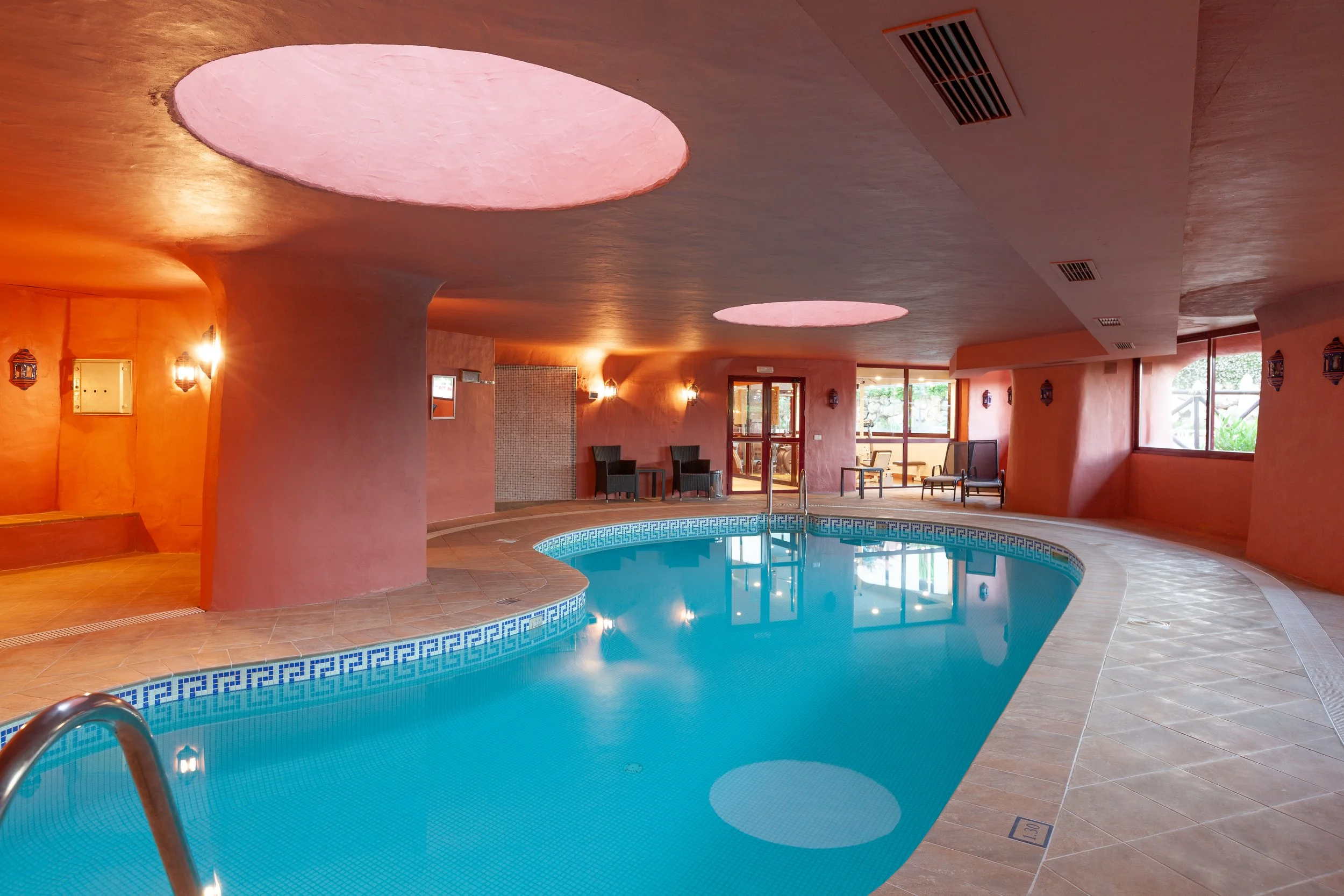 Wellness center featuring a heated indoor swimming pool with architectural skylights and ambient lighting.