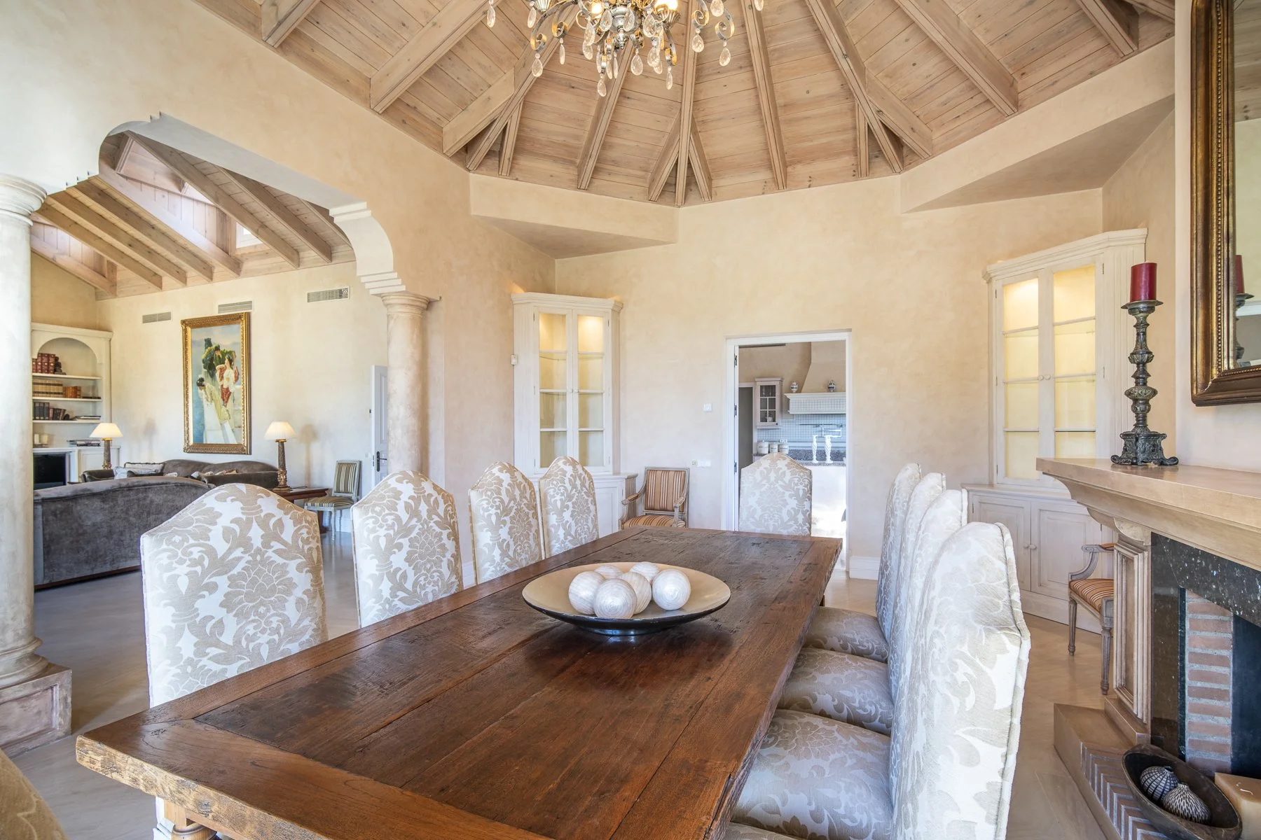 Formal dining room under a dramatic wooden-beamed ceiling, reflecting Mediterranean luxury.