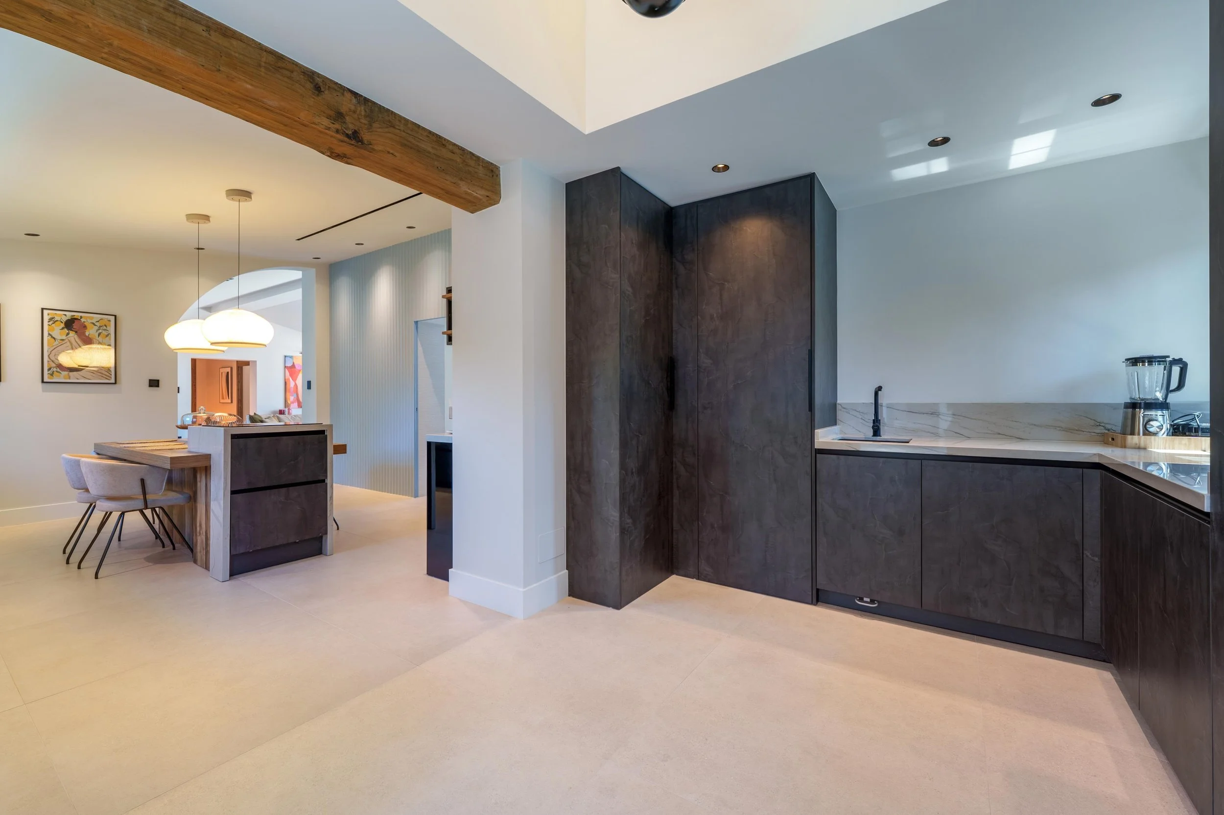 Highlighting the central island and custom cabinetry.  Alt-Text: Luxury minimalist kitchen with dark cabinetry and a large central island.