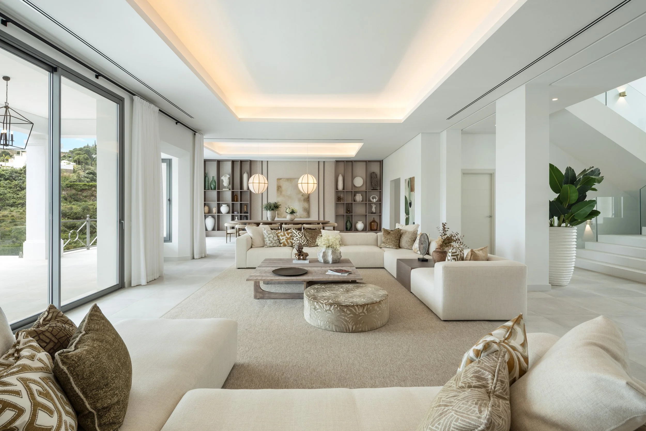 The expansive, double-height living room featuring floor-to-ceiling windows that flood the modern interior with natural light.