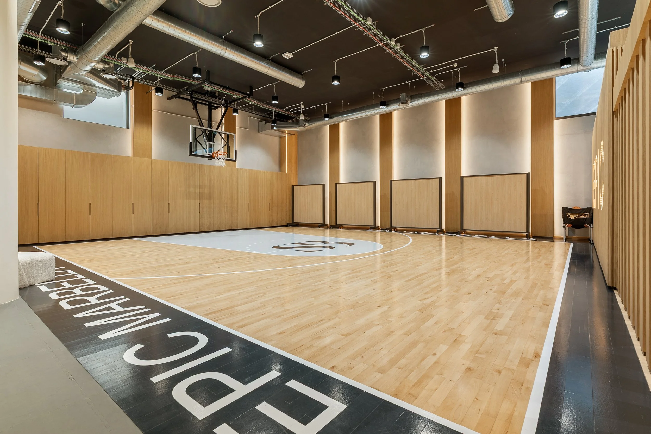 A private indoor sports court, likely for basketball or training, featuring high-quality wood flooring and "EPIC" branding on the sidelines.