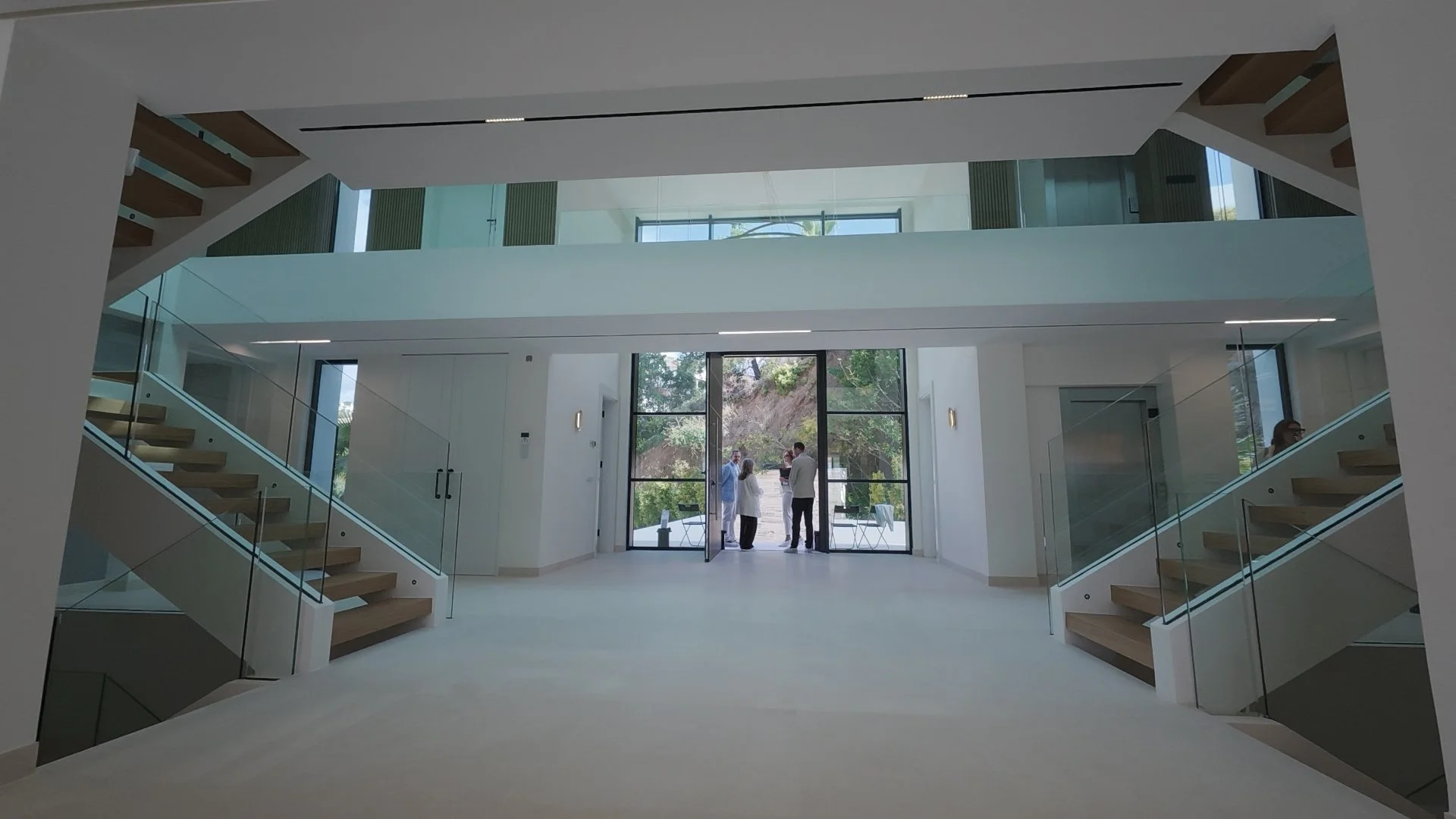 Grand Entrance Hall: Captured from our tour, this shot shows the dramatic double-staircase entry with a direct sightline through the glass doors to the Mediterranean horizon.