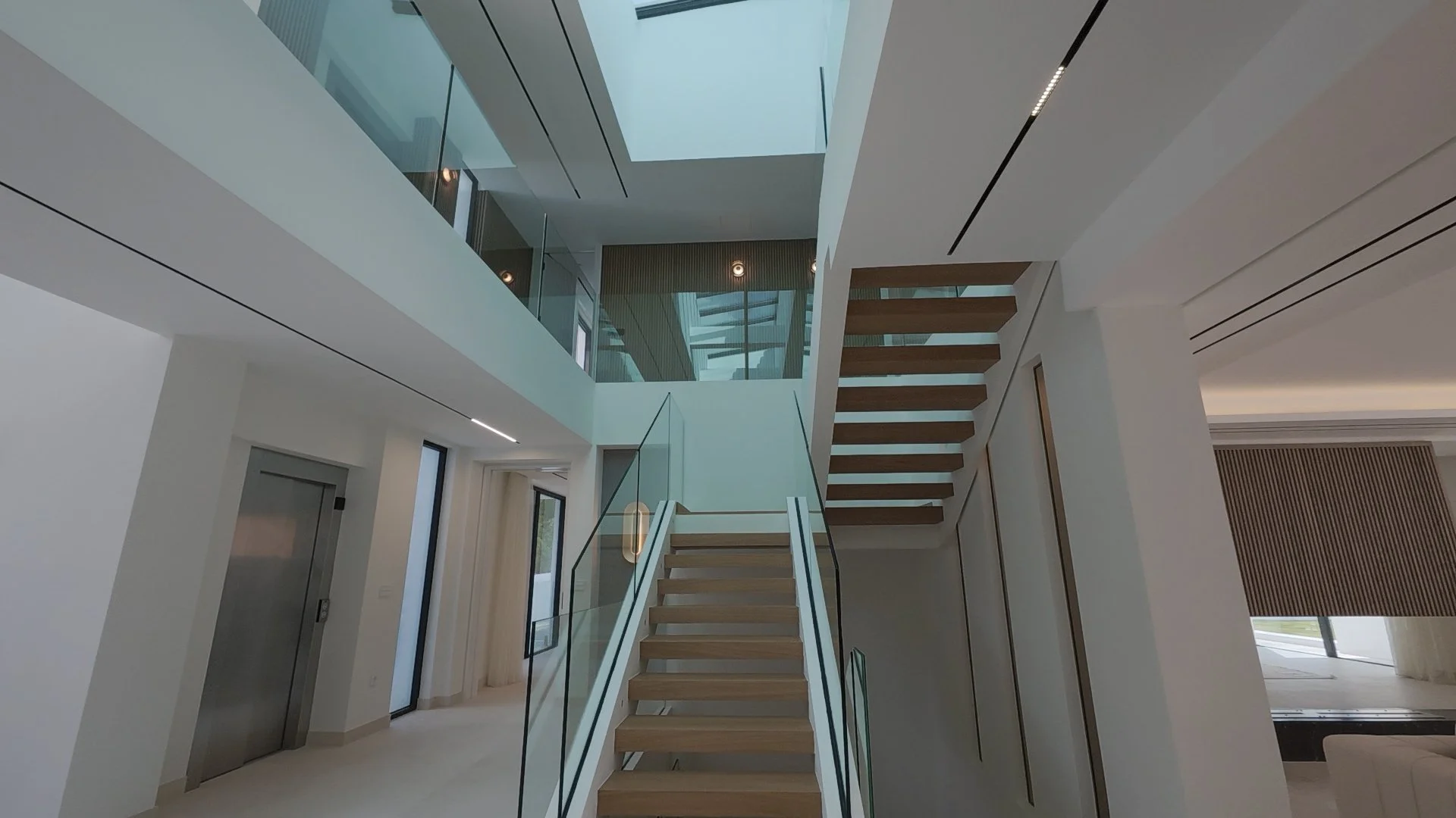 Grand Entrance Hall: Captured from our tour, this shot shows the dramatic double-staircase entry with a direct sightline through the glass doors to the Mediterranean horizon.
