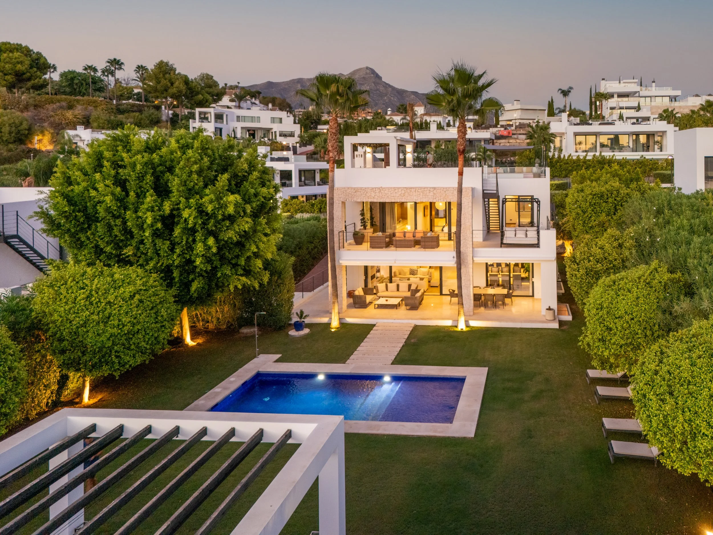 Luxury contemporary villa Los Olivos 2 in Nueva Andalucía at dusk, featuring a private illuminated pool and modern architectural lighting.