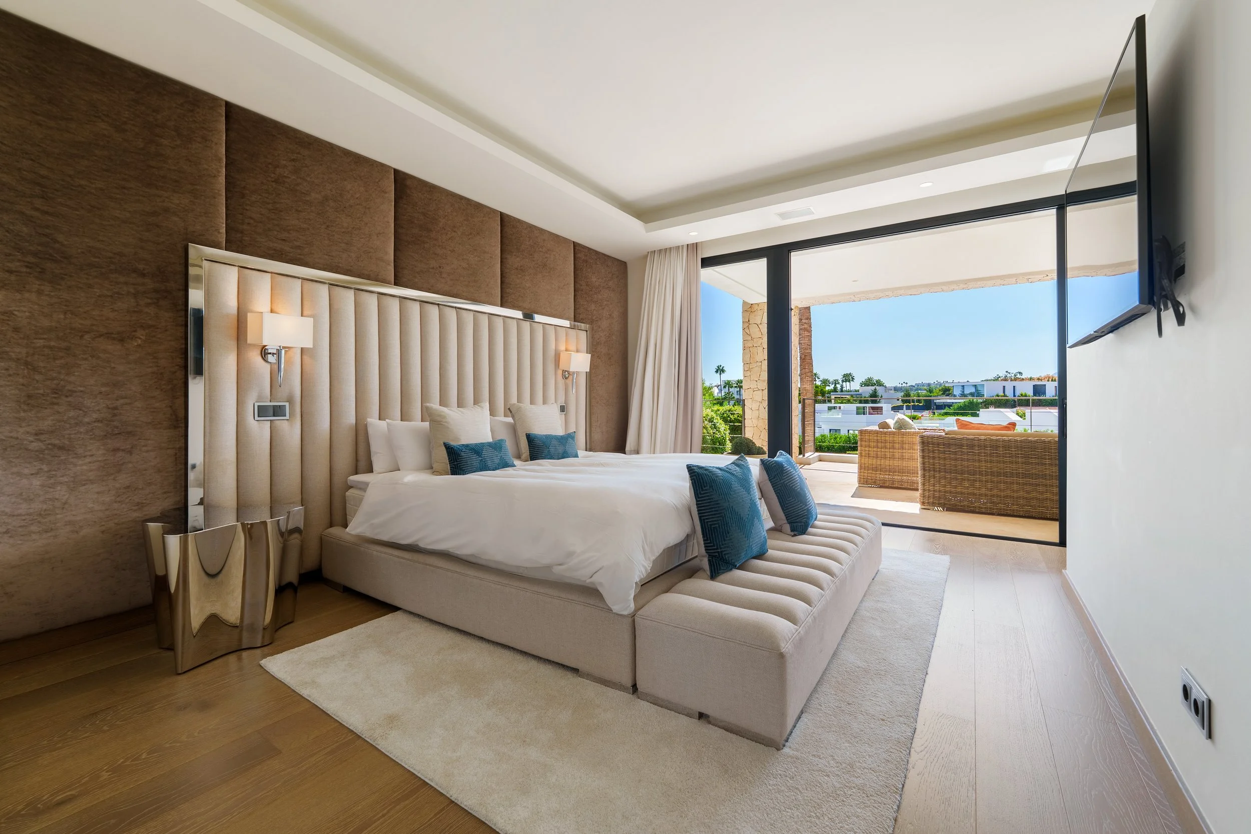 Spacious master bedroom with modern wood paneling, floor-to-ceiling windows, and direct access to a private sun terrace.