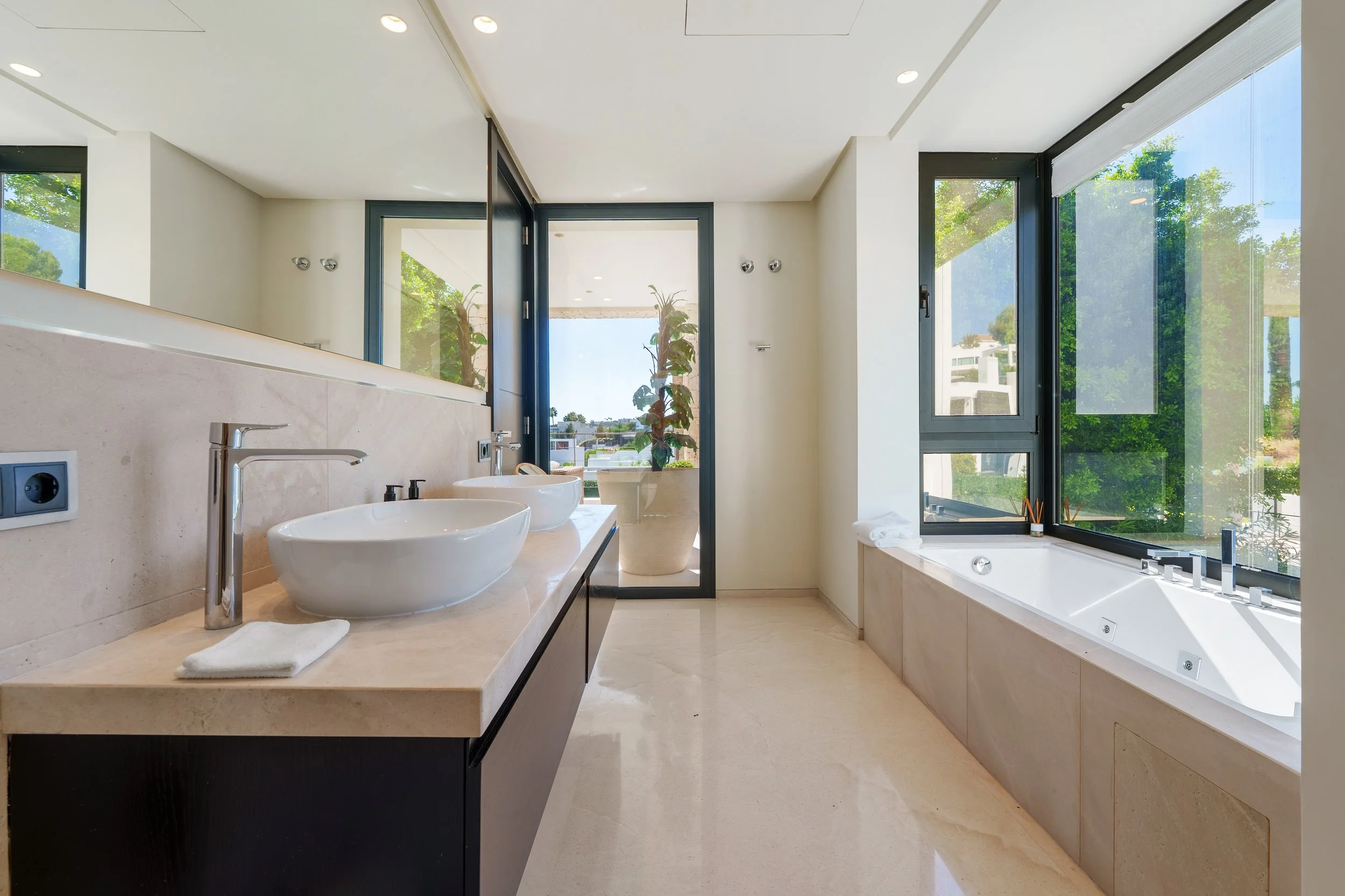 Minimalist master bathroom featuring a deep soaking tub, walk-in rainfall shower, and sleek vanity with double sinks.