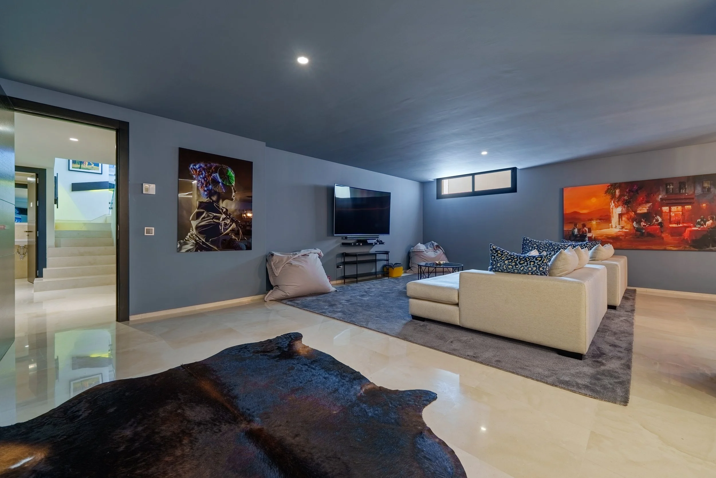 Private entertainment lounge with deep plush seating, large screen, and contemporary artwork for a boutique cinema experience.