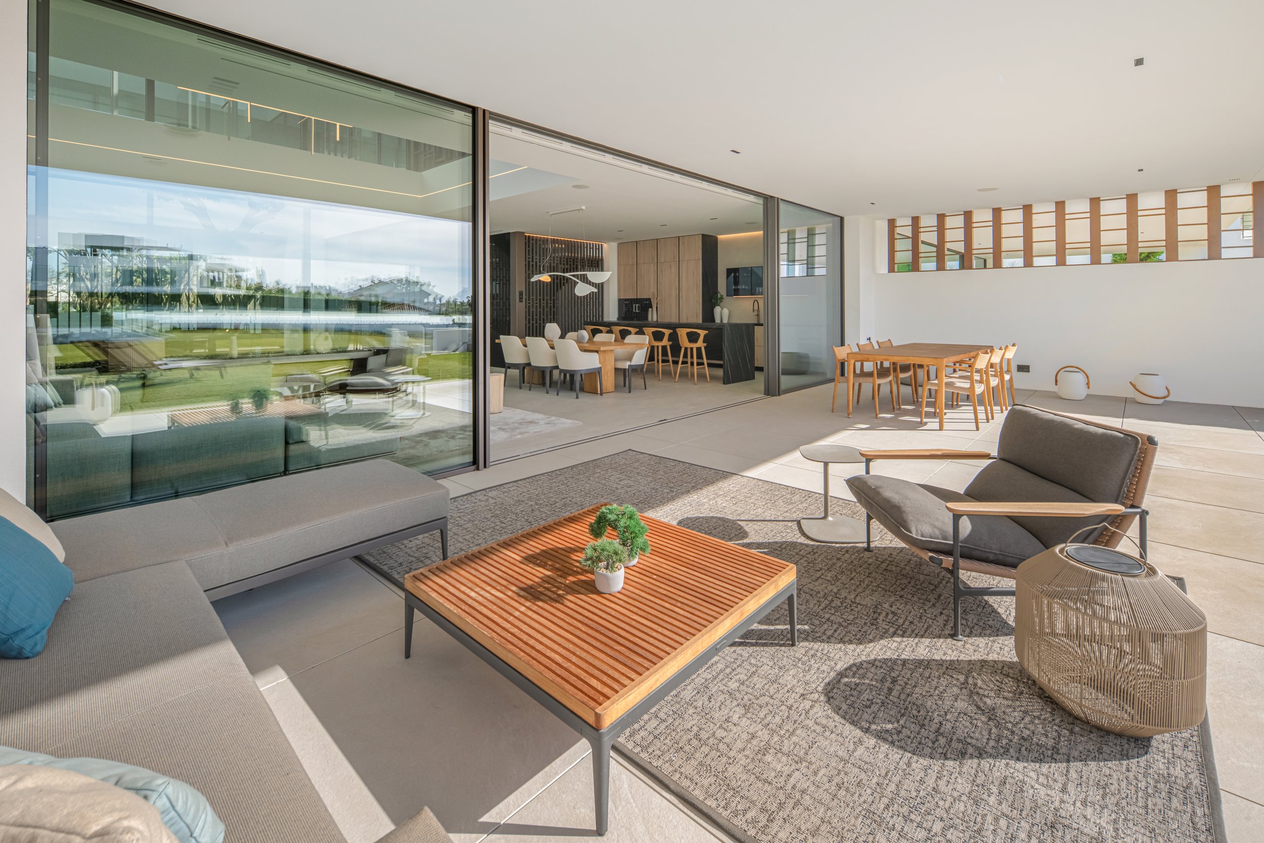 Sun-drenched living area with floor-to-ceiling glass doors opening directly onto a private manicured garden