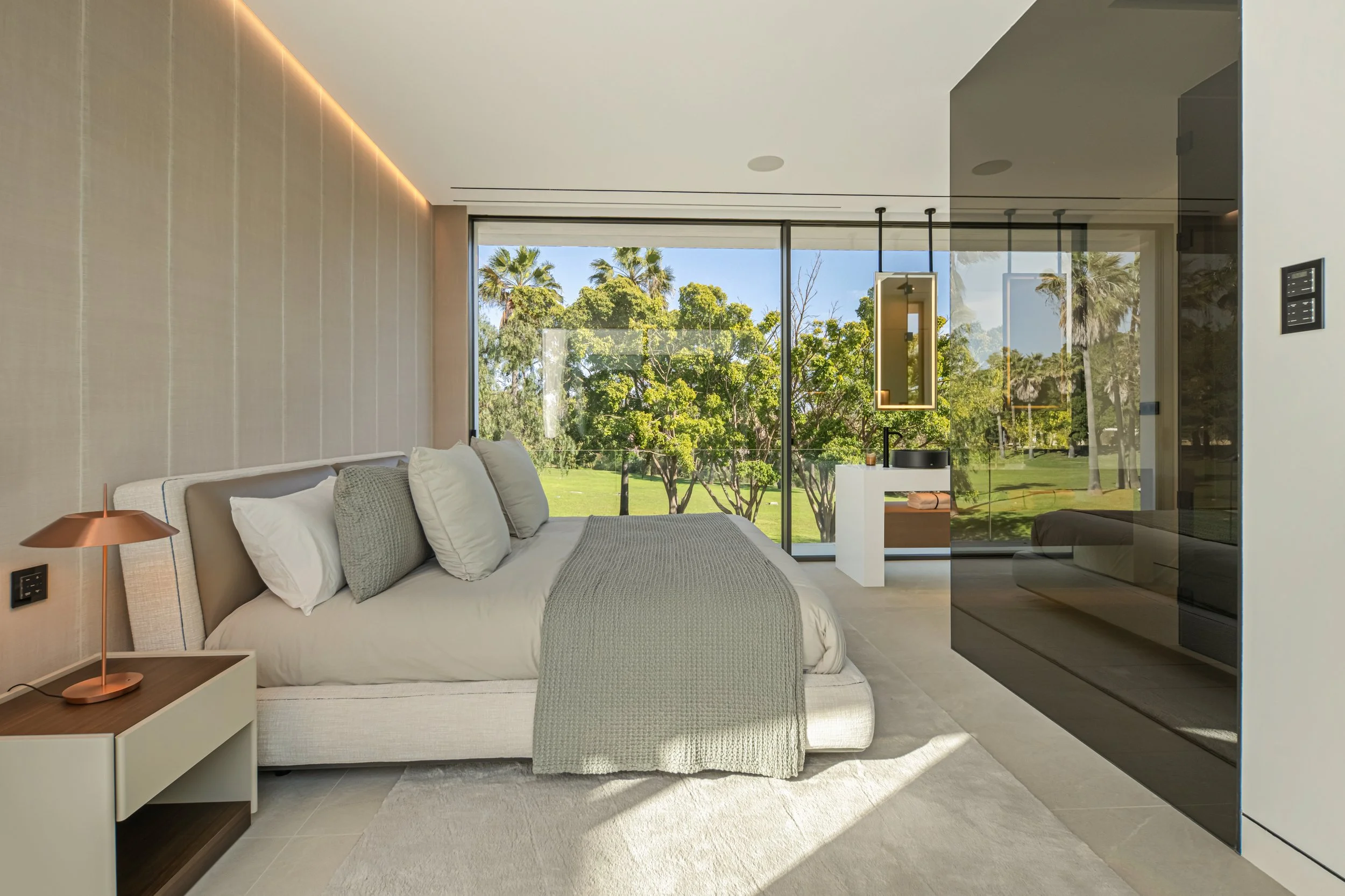 Spacious bedroom featuring clean lines, warm ambient lighting, and high-end built-in wardrobes.