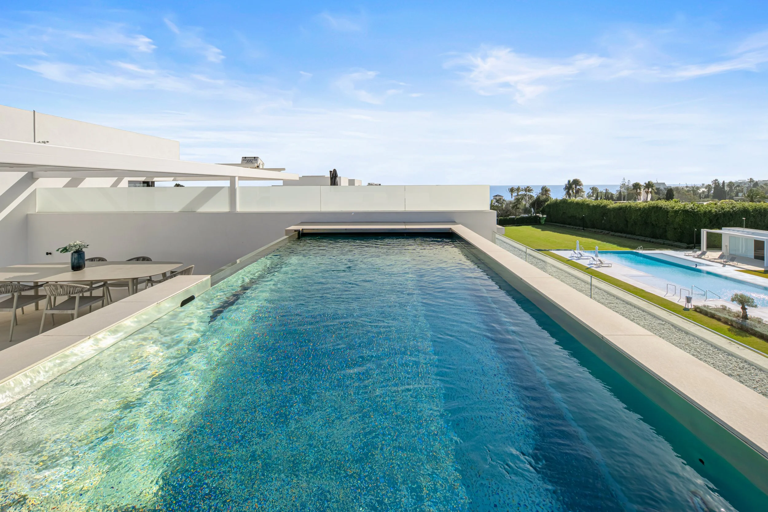Private rooftop infinity pool with glass wall feature, overlooking the surrounding luxury estate
