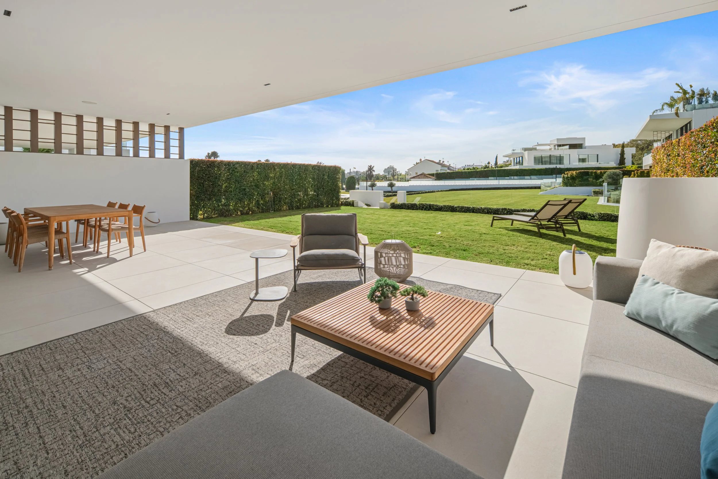 Lower terrace lounge area with seamless access to the private lawn and Mediterranean landscaping.