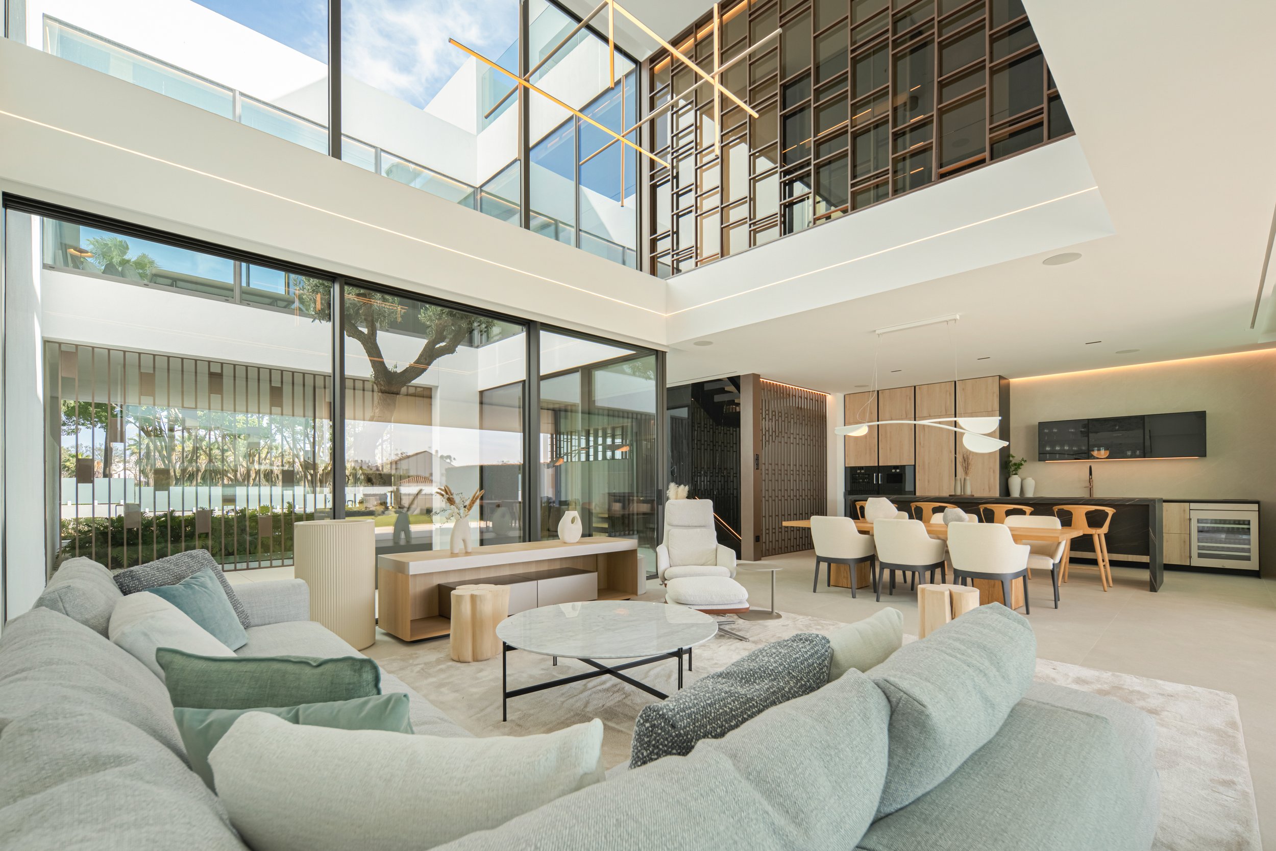 Expansive double-height living room with contemporary furniture and views into the glass-walled garden atrium