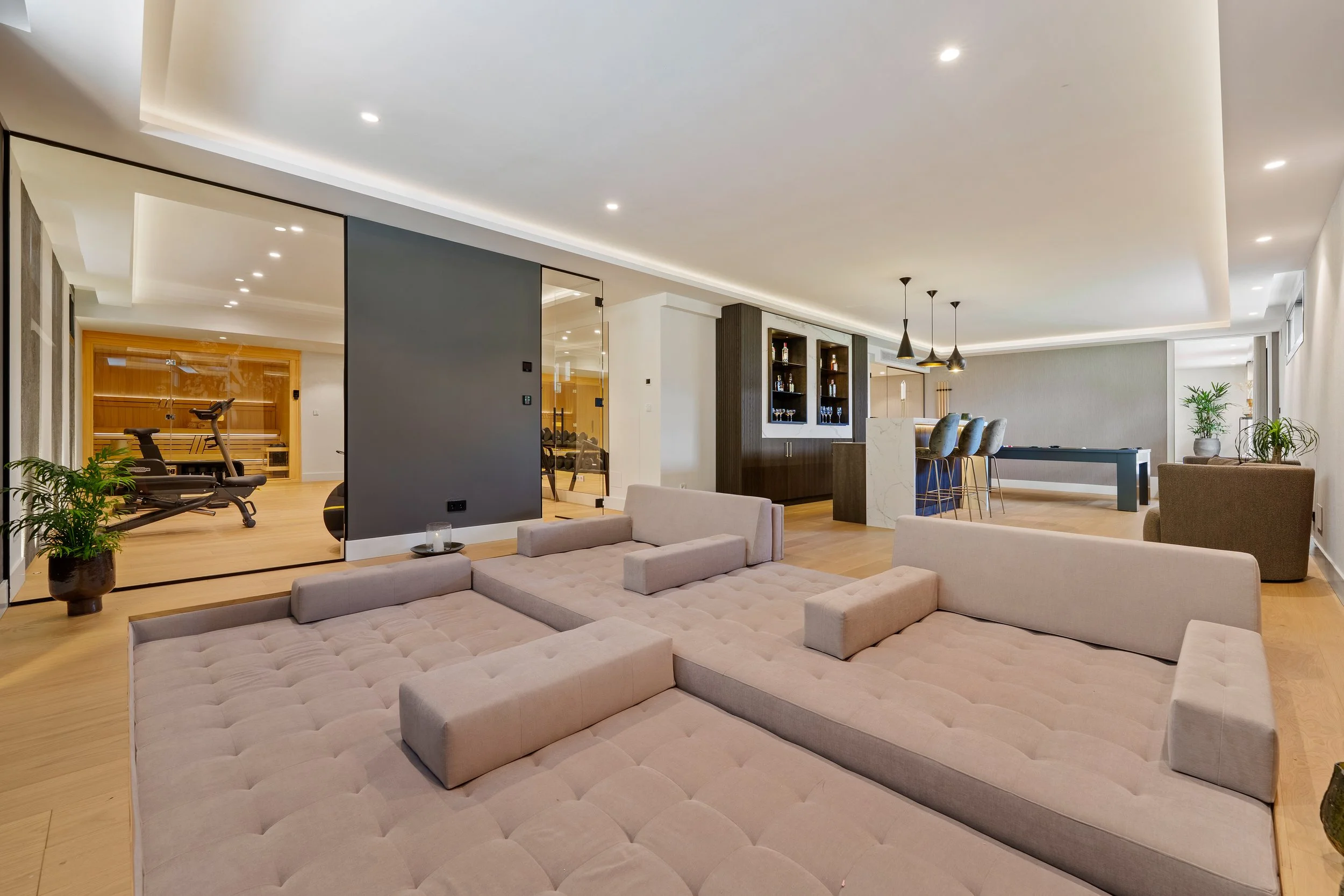 Contemporary open-plan lounge area with designer lighting and oak flooring.
