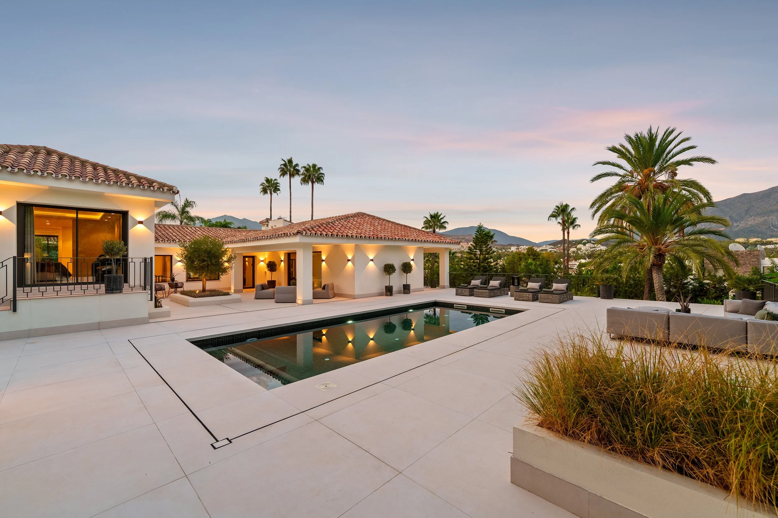 Private illuminated swimming pool and terrace during a sunset open house tour.