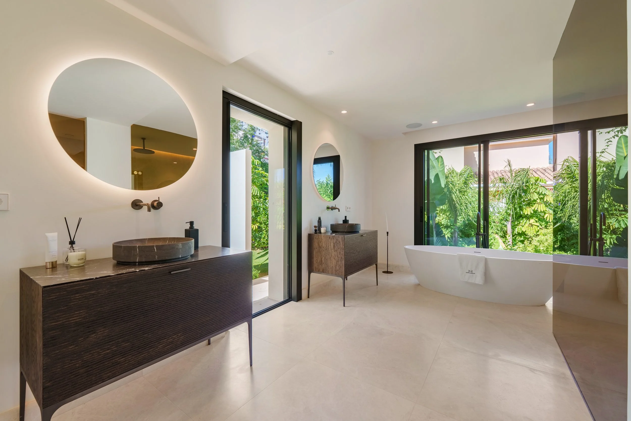 Modern bathroom featuring a circular LED mirror and premium finishes.