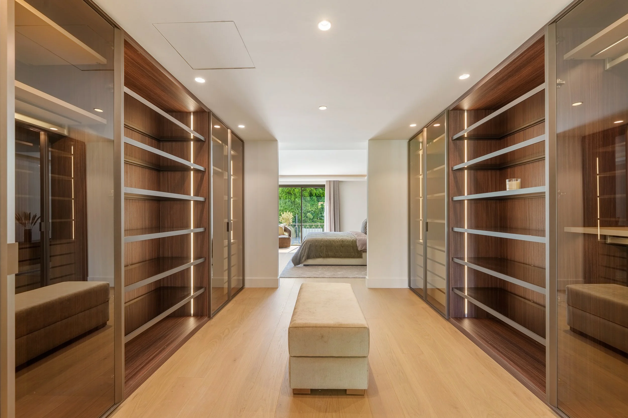 Expansive custom walk-in wardrobe with integrated lighting and oak wood.