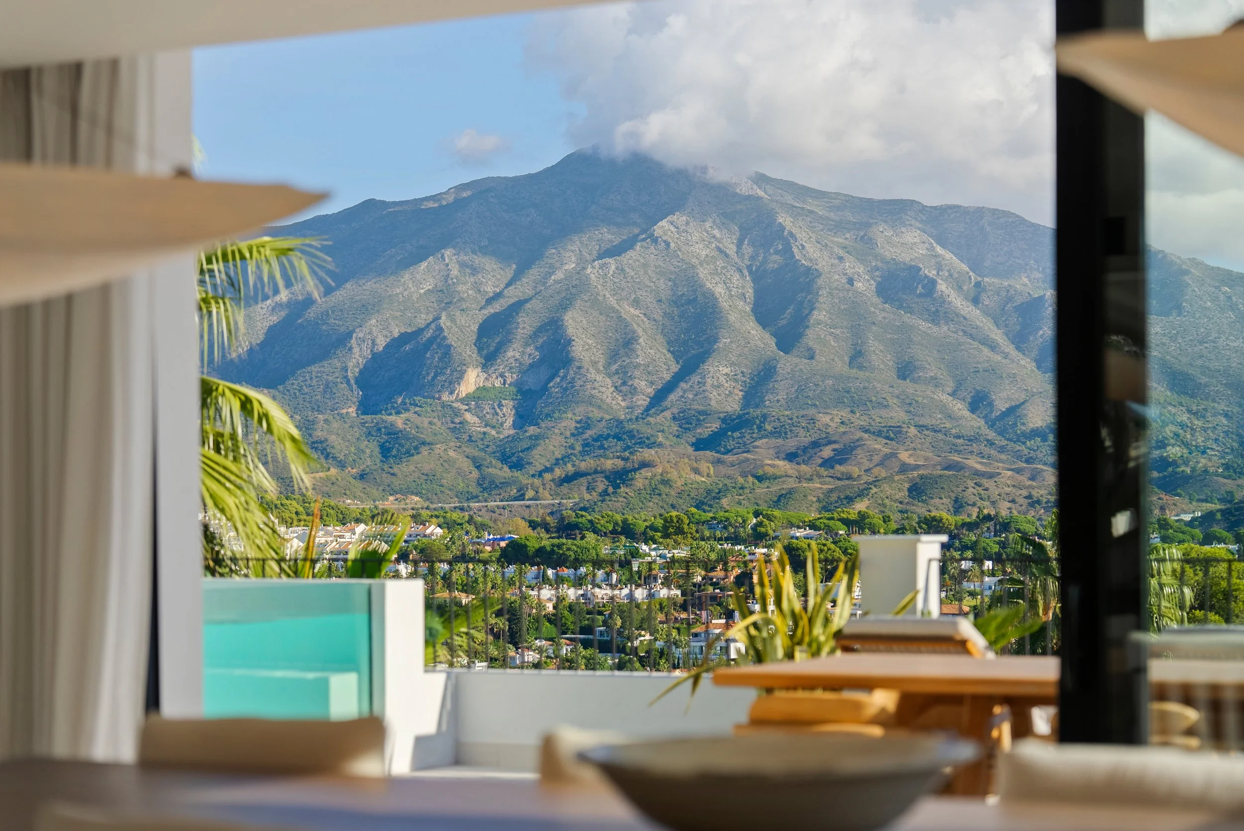 Open-plan living area featuring floor-to-ceiling glass walls that merge the interior with the terrace.