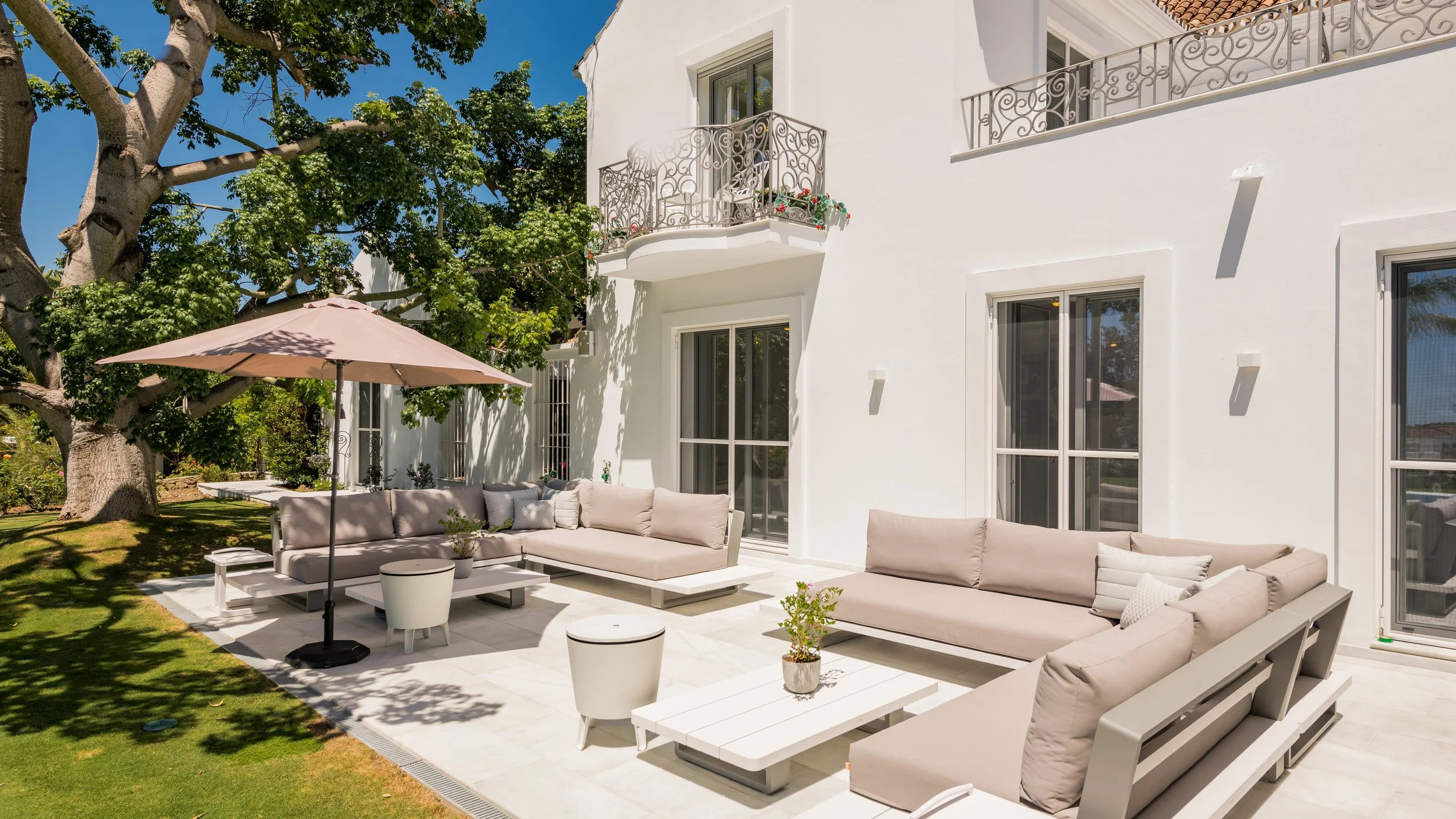 Modern outdoor garden lounge with white sofas fire pit and manicured lawn in La Cerquilla villa Nueva Andalucia Ref CMH2440