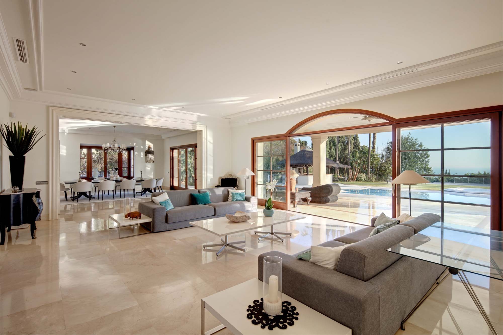 Open-plan luxury living room with marble flooring and floor-to-ceiling sliding glass doors.