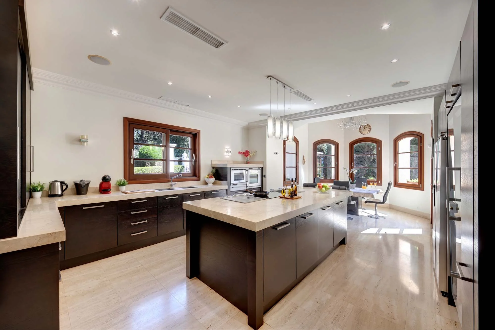 Contemporary dark wood kitchen with central island, breakfast area, and integrated Gaggenau appliances.