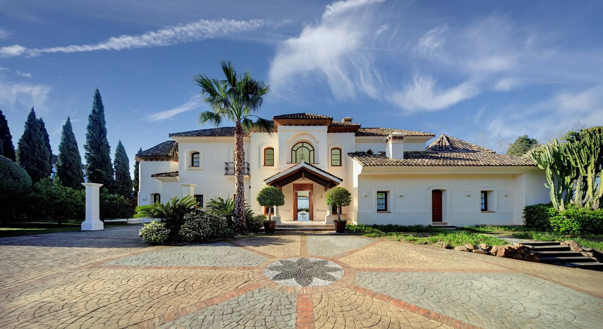 Wrought iron entrance gates and grand courtyard driveway of a luxury estate on Marbella Golden Mile.