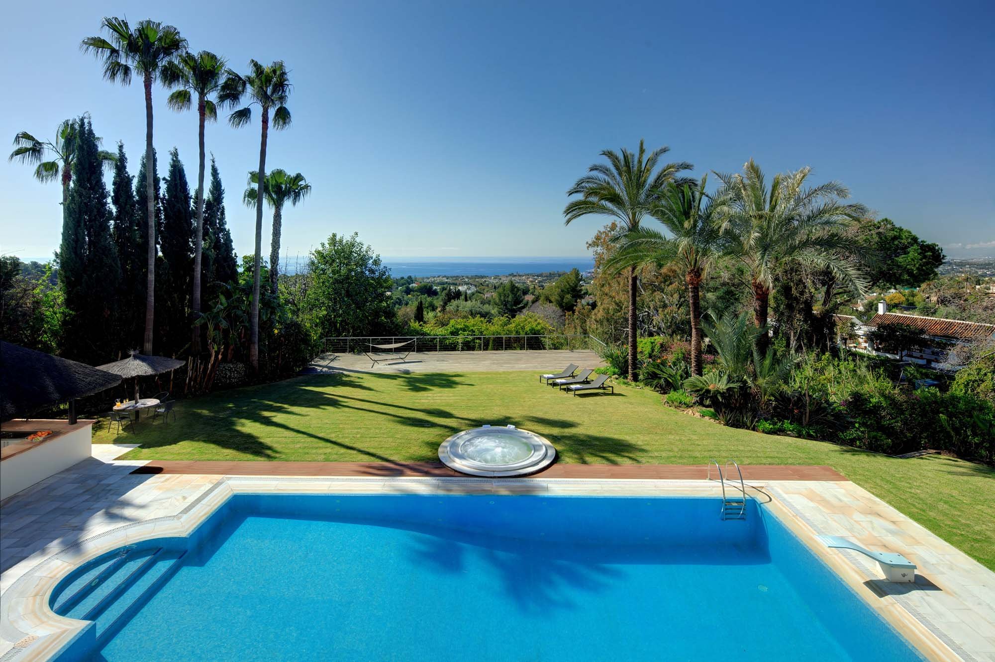 Premium heated swimming pool with sunbeds and pristine lawns on the Marbella Golden Mile.