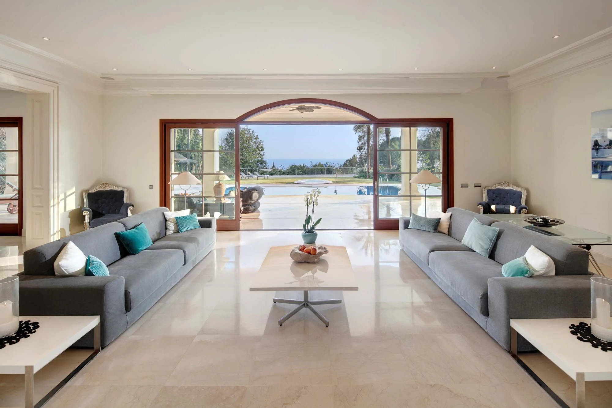Contemporary salon with polished marble floors, comfortable seating, and sliding doors to the garden.
