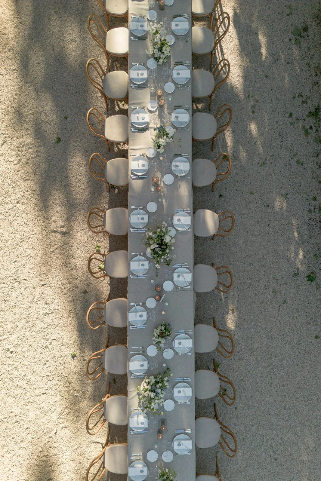 Top-down view of an elegantly set outdoor dining table at Chateau de Mille in Provence (Luberon région), floral centerpieces, and place settings including plates, glasses, and cutlery.