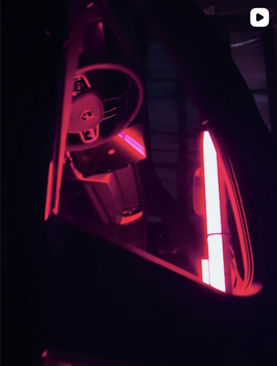 Interior of a Volvo illuminated with pink and red LEDs by Eventsolution cooperating with MotionLab Visuals on Instagram, showing the steering wheel and dashboard.