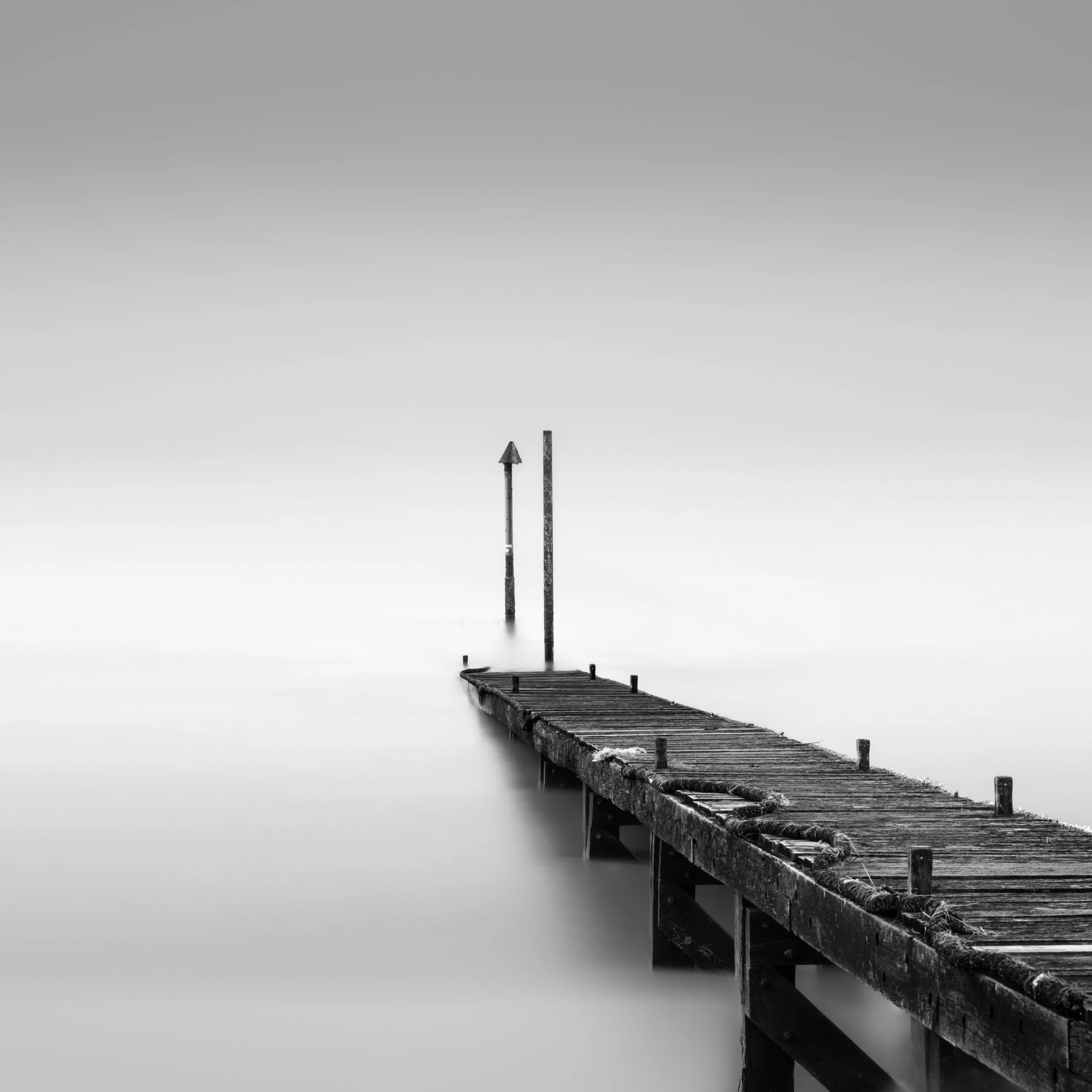 fine art minimalist image of a wooden pier extending in to nothingness 