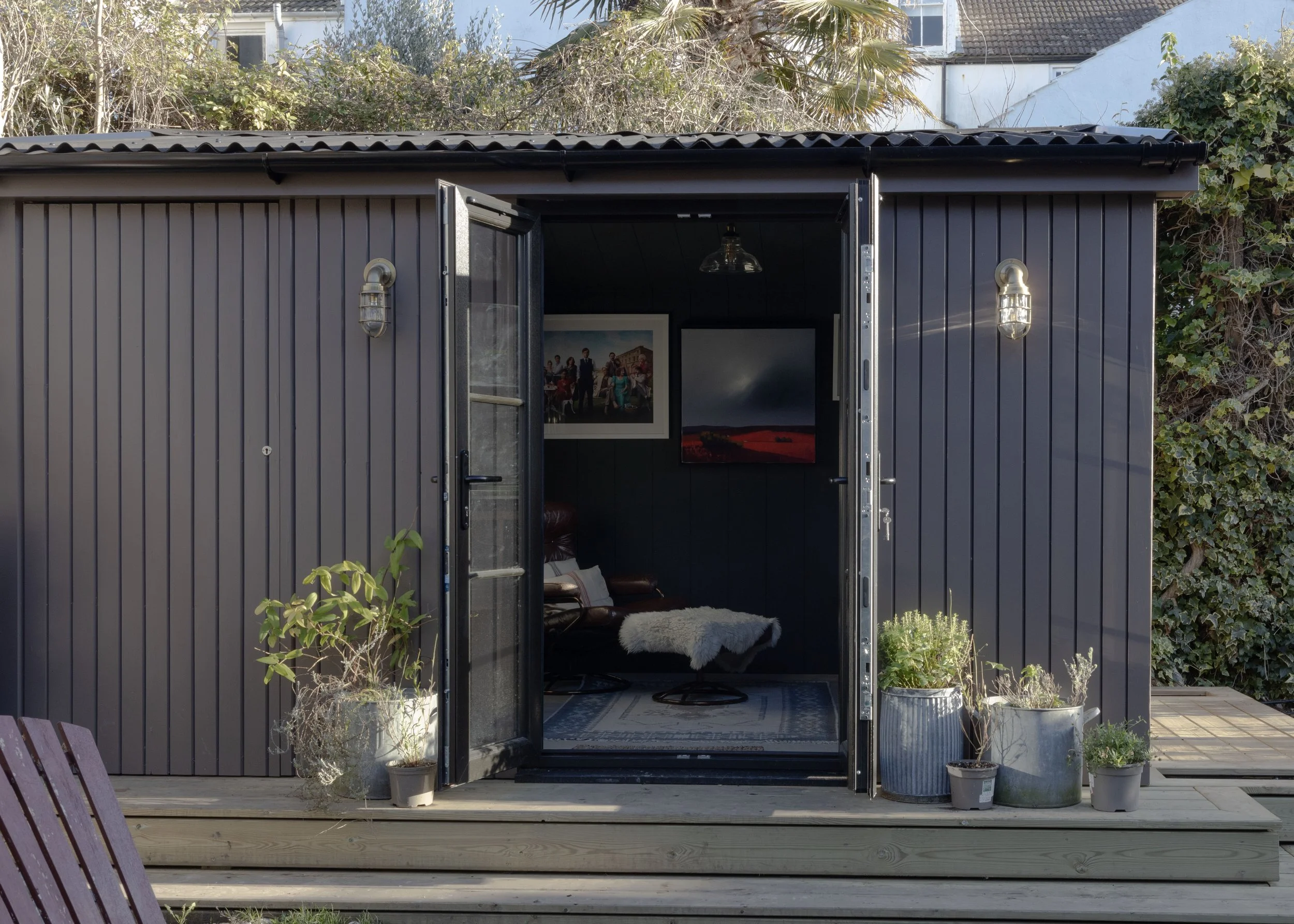 A custom garden office was designed and finished in London Stone by Farrow and Ball. Vintage lighting was added and the interior was painted in Studio Green and covered in art work with vintage furniture. 