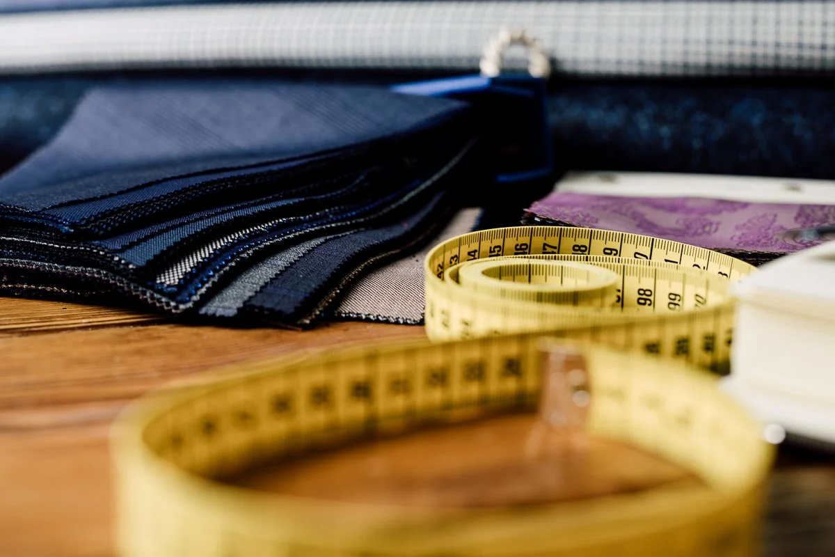 Various fabric swatches and a yellow measuring tape on a wooden surface.