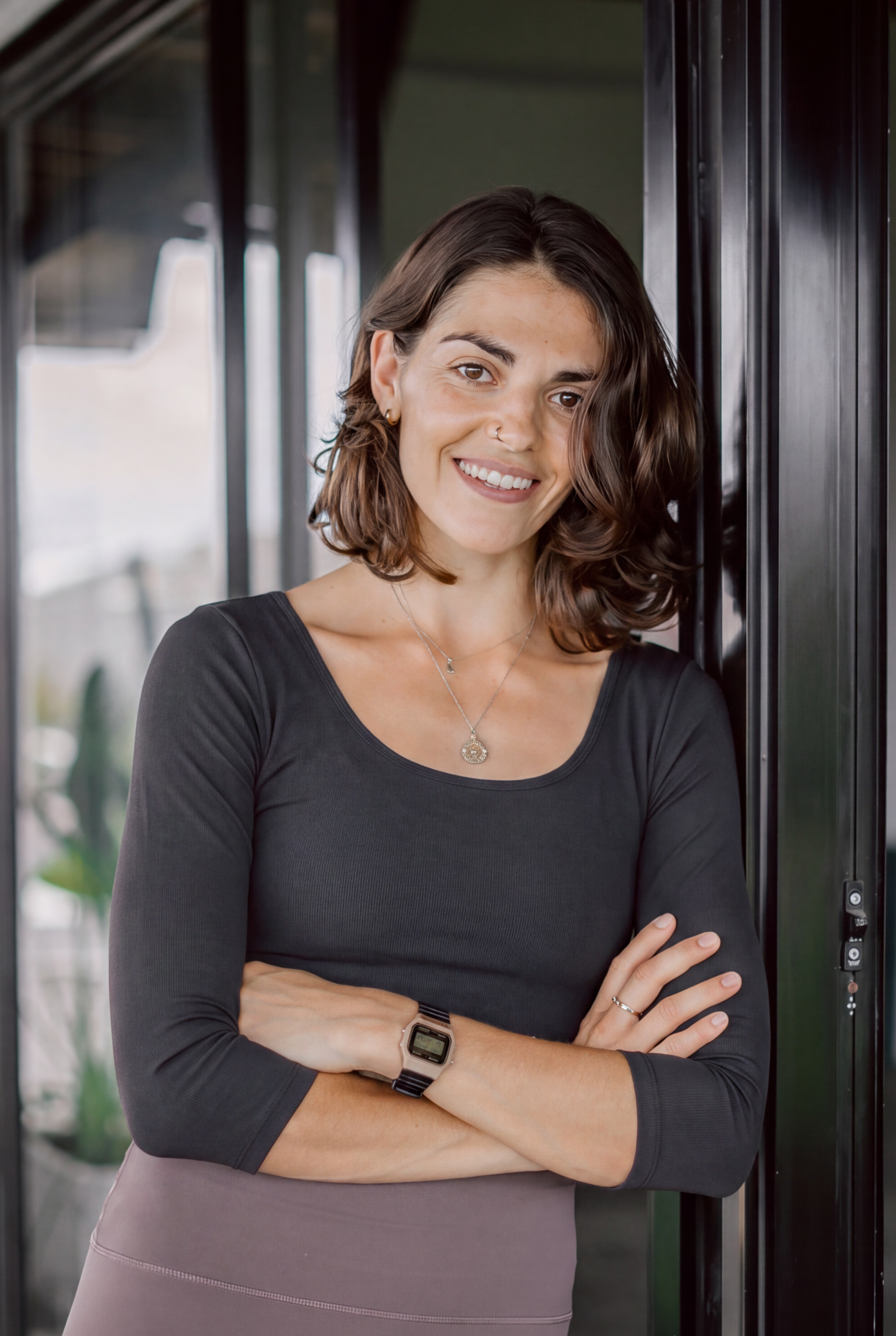 Headshot picture of therapist Ester Oldfield, a brunette woman leaning against a door frame in a black top