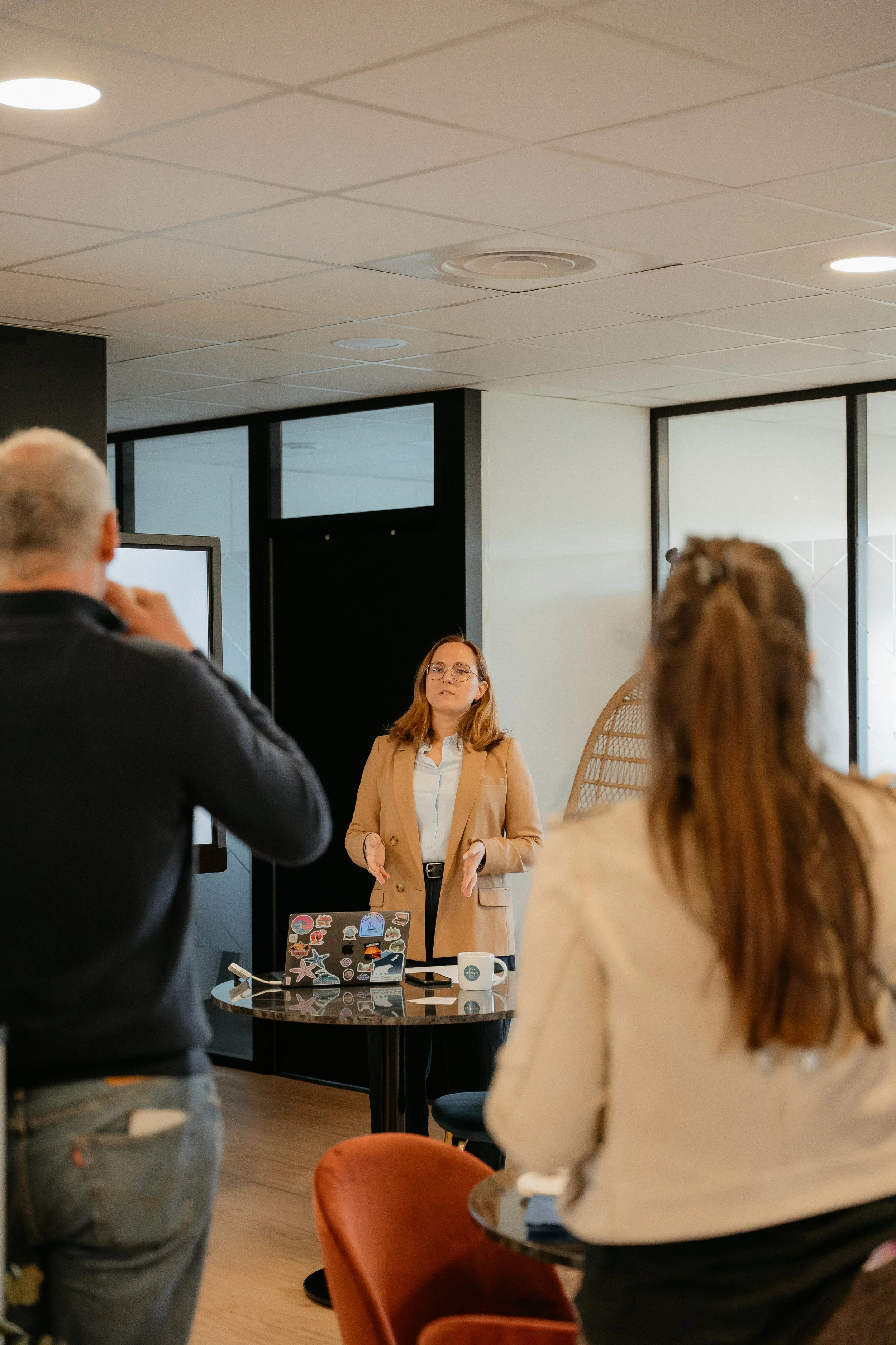 Une femme en train de faire une présentation à un groupe de personnes dans une salle moderne.