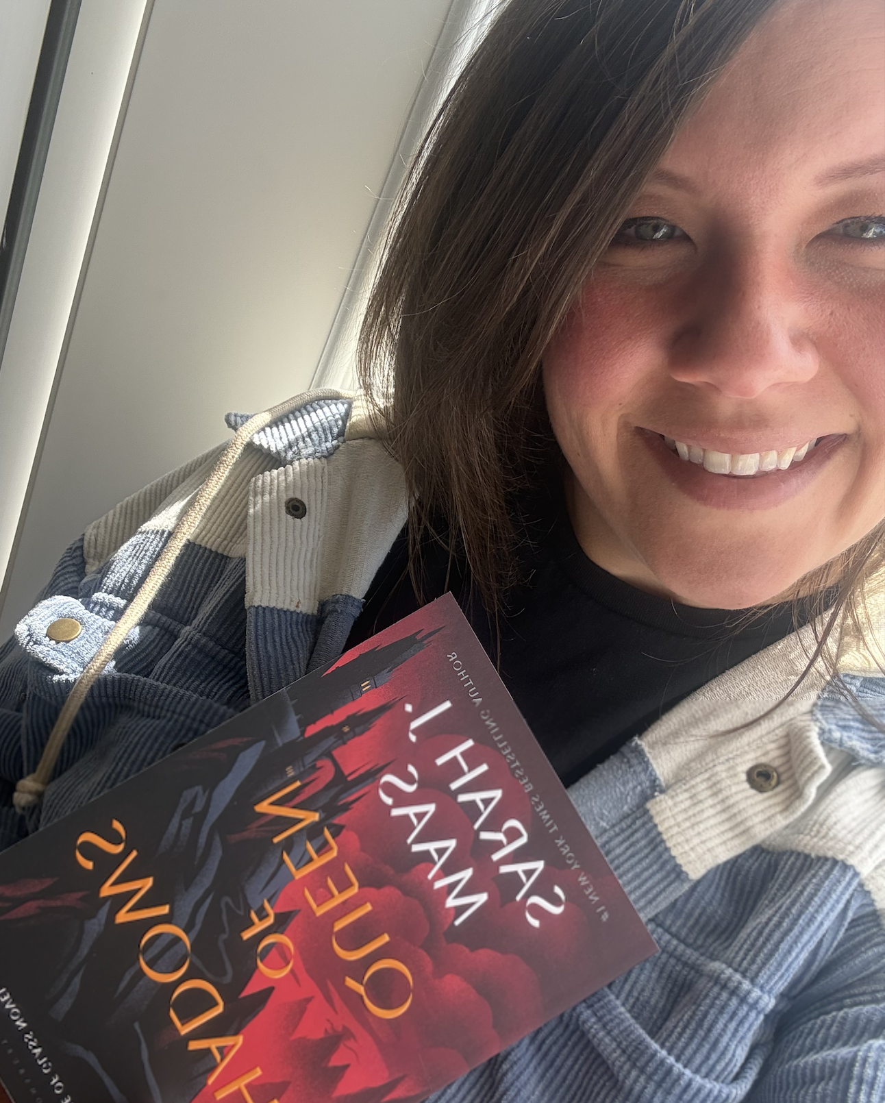 A smiling woman with shoulder-length brown hair and light makeup holding a book about a wildfire.