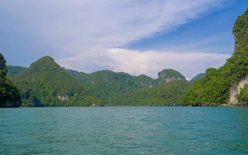 A scenic view of lush green mountains surrounding a body of water under a partly cloudy sky.