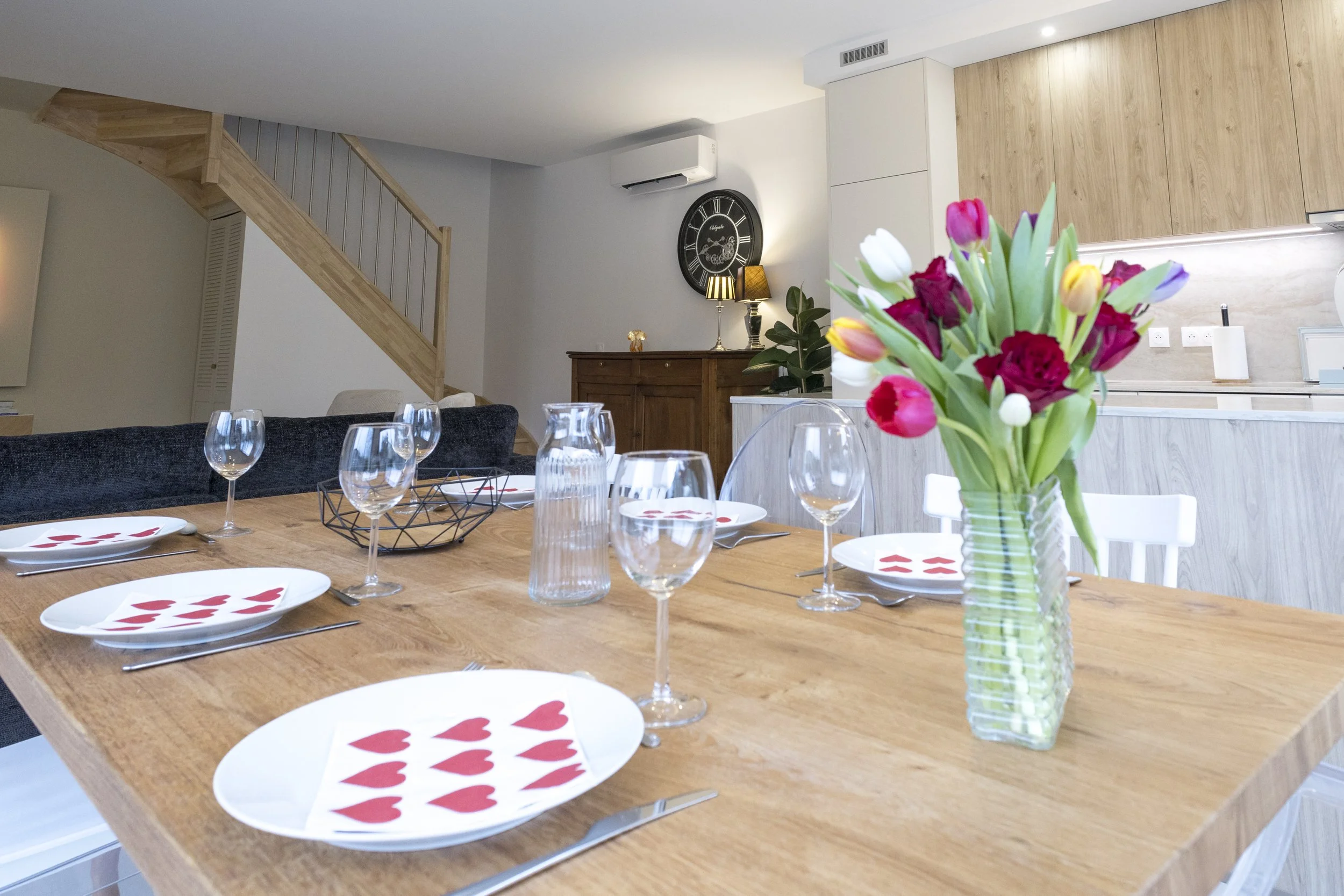 Table de dîner dans une salle moderne, décorée avec un vase rempli de tulipes rouges, roses et blanches.