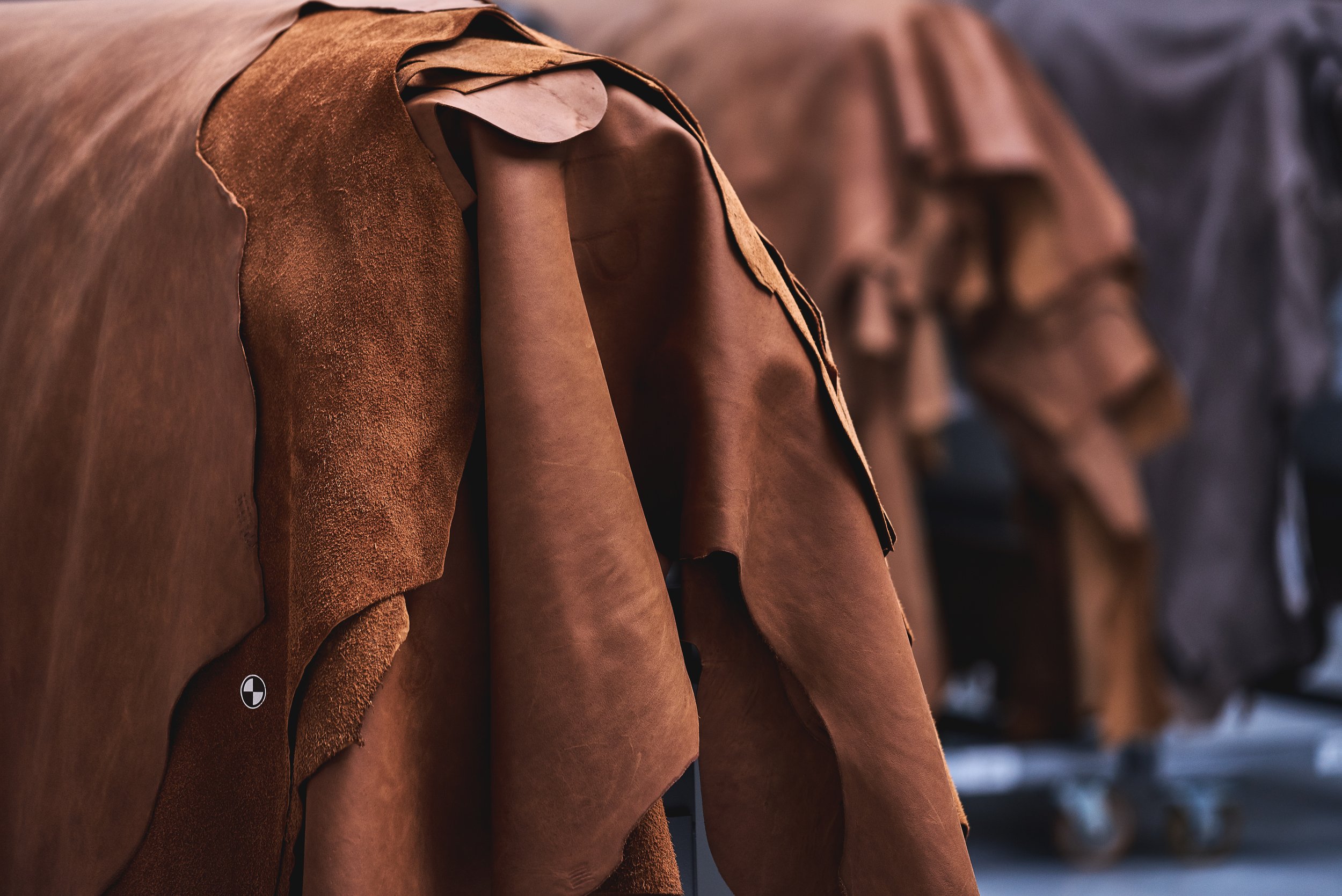 Close-up of brown and black leather and suede jackets hanging on display.