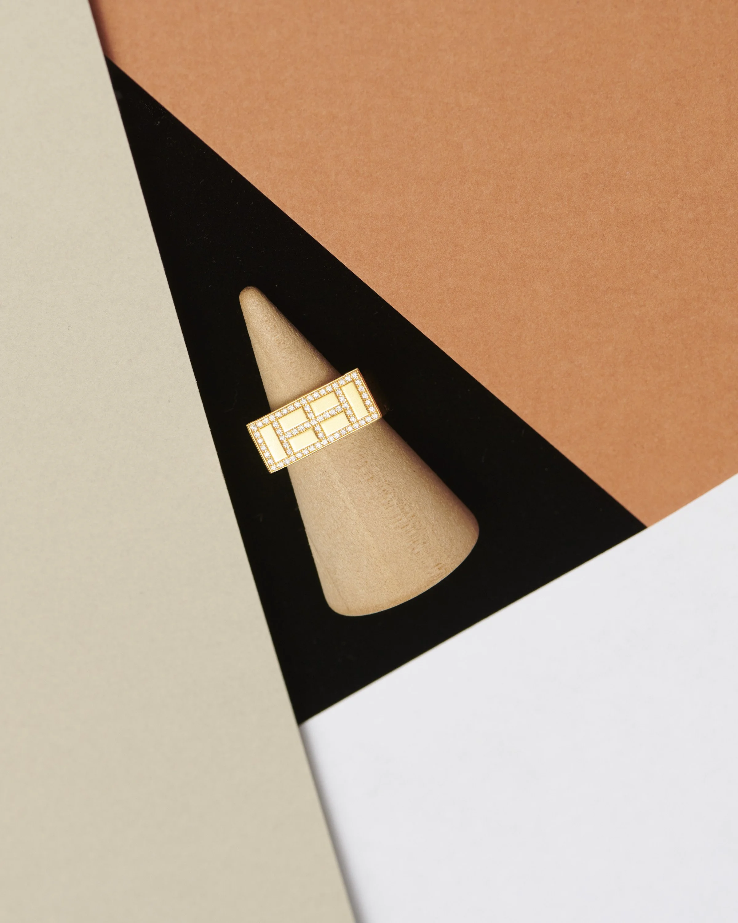 Une bague en or avec des diamants et une pierre centrale sur un doigt.