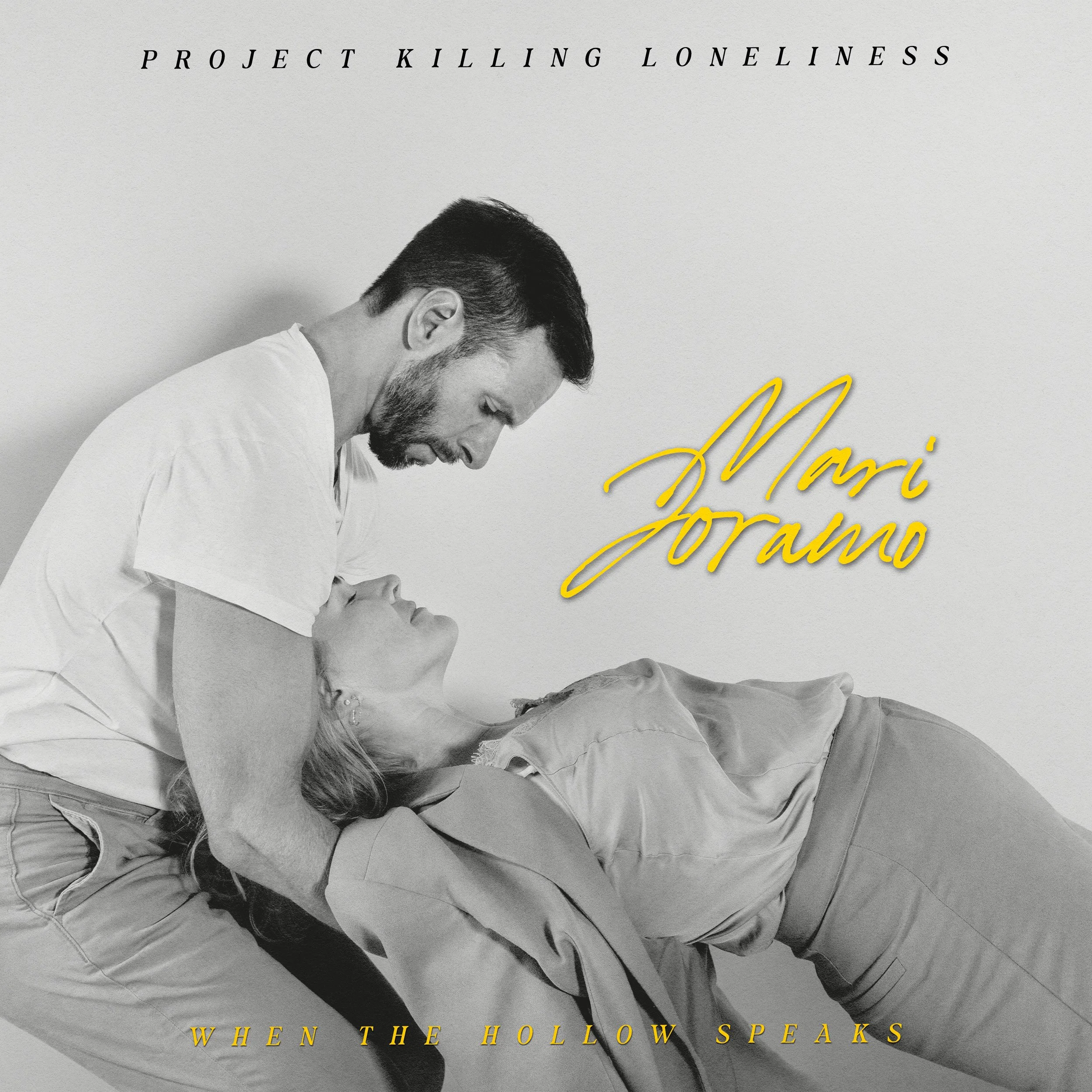 Black and white image of a man leaning over a woman, hugging her as she lies on the floor. The woman is reclined and the man is looking down at her. The text reads 'Mári Joramo' in yellow cursive, and at the top, it says 'Project Killing Loneliness' in small uppercase letters. At the bottom, it says, 'When the Hollow Speaks' in yellow uppercase letters.