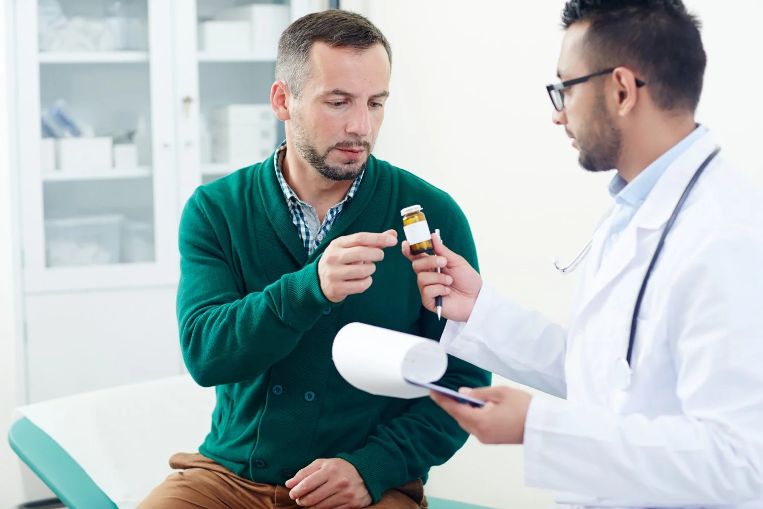 Doctor handing medication bottle to patient in medical office.