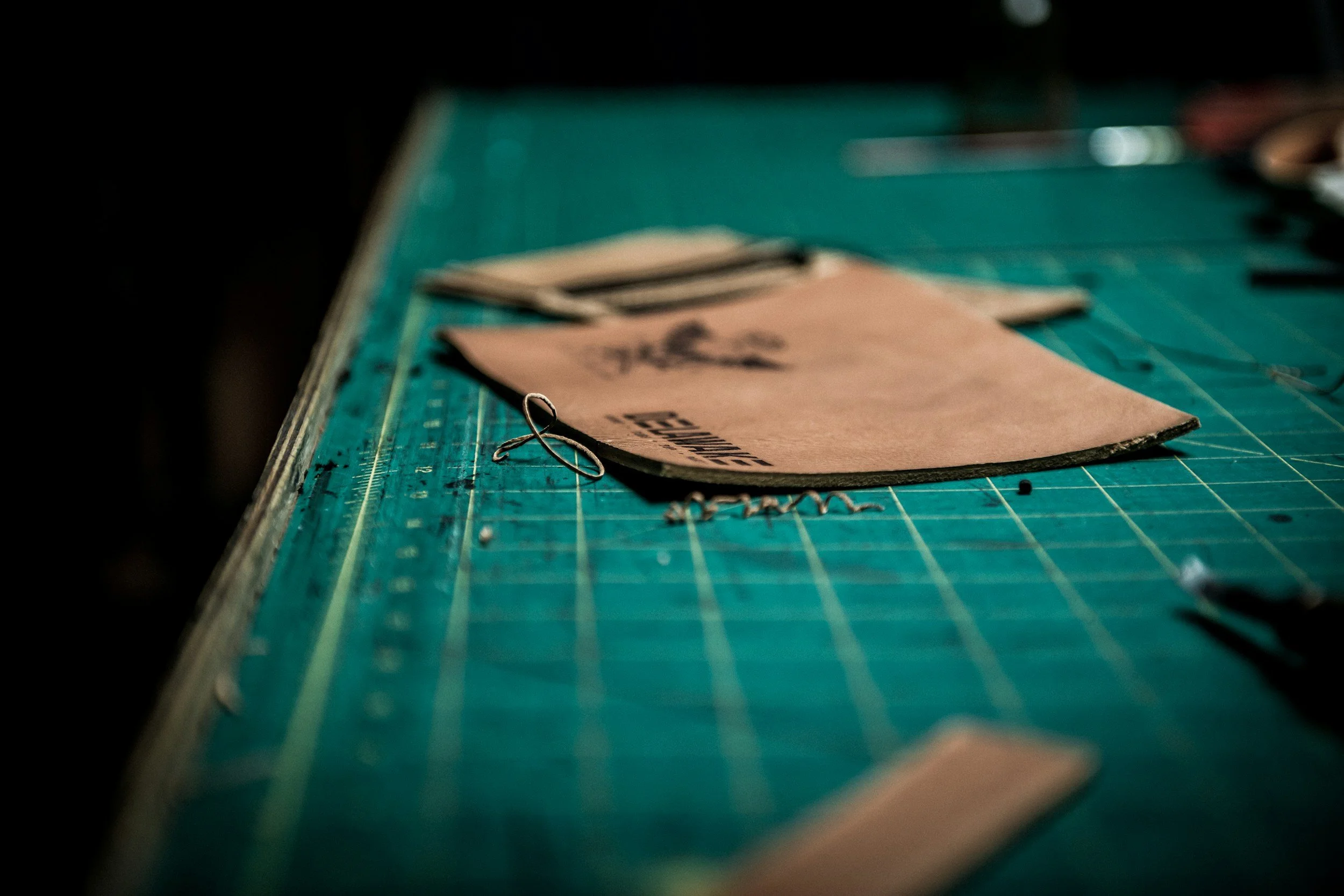A close-up view of a green cutting mat with cut-out fabric pieces, strings, and scissors on it.
