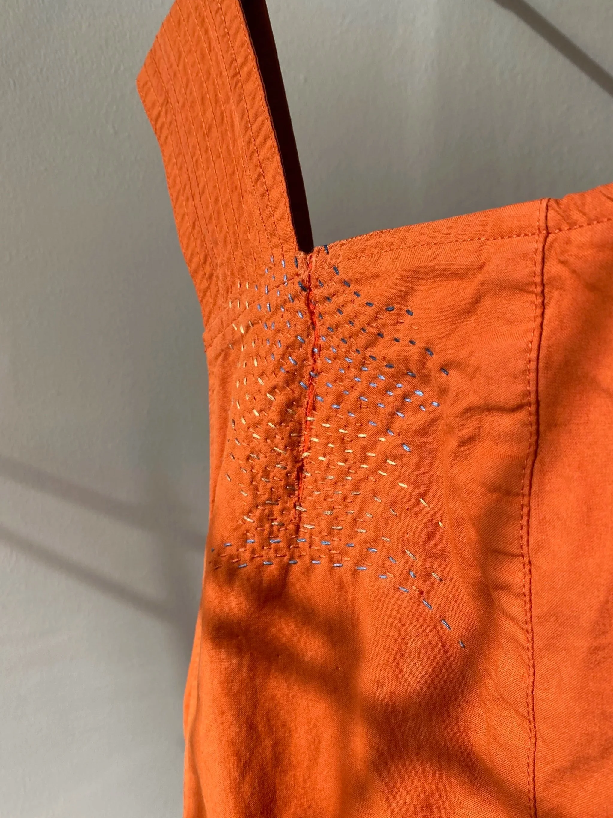 Visible sashiko inspired repair with patch on matching fabric on reverse, stitched in place with waves of straight stitches in yellow, light blue and navy